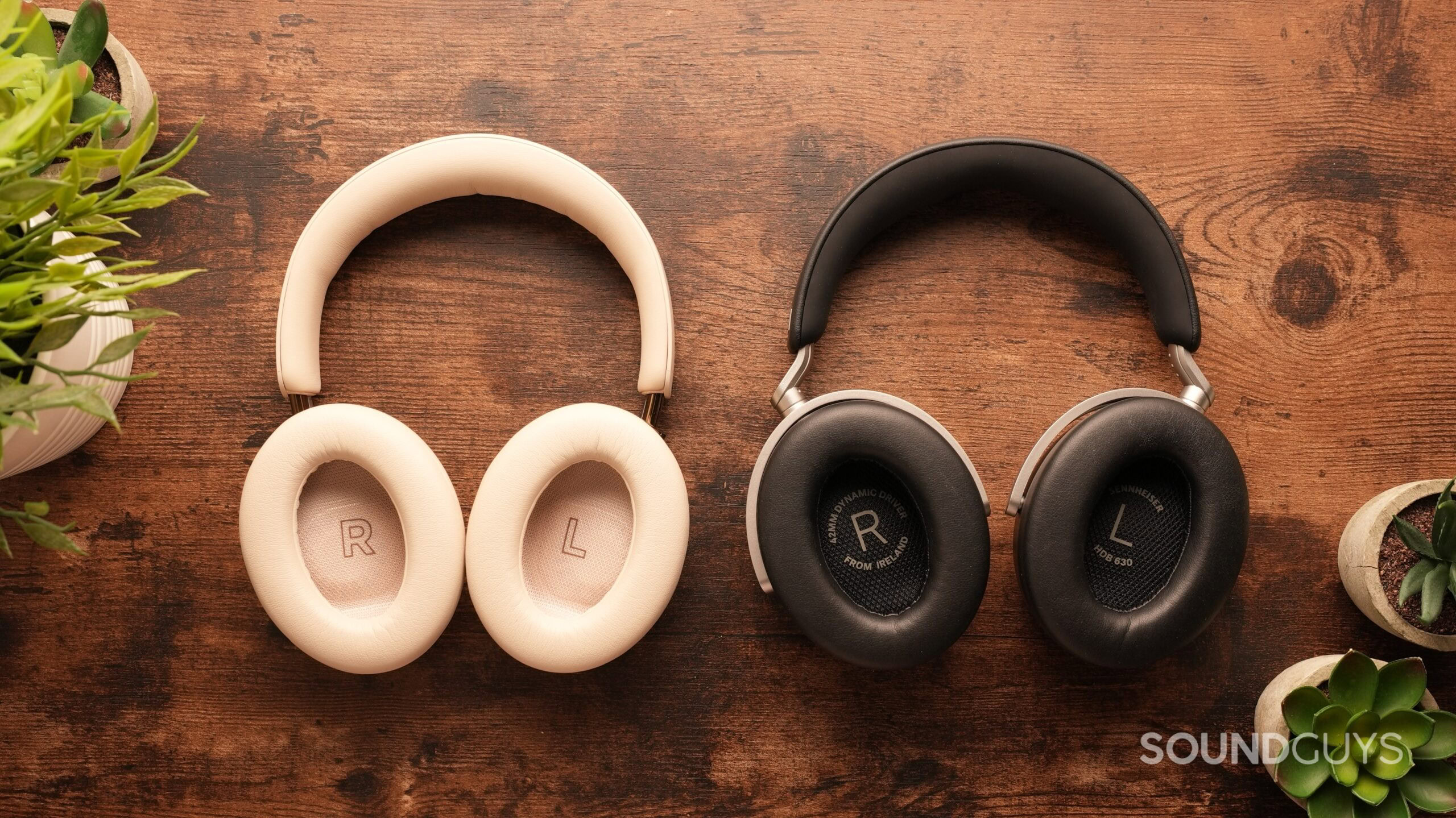 bose-quietcomfort-ultra-2-vs-sennheiser-hdb-630-2 The Bose QuietComfort Ultra 2s and the Sennheiser HDB 630s sit side-by-side on a table, cups up.