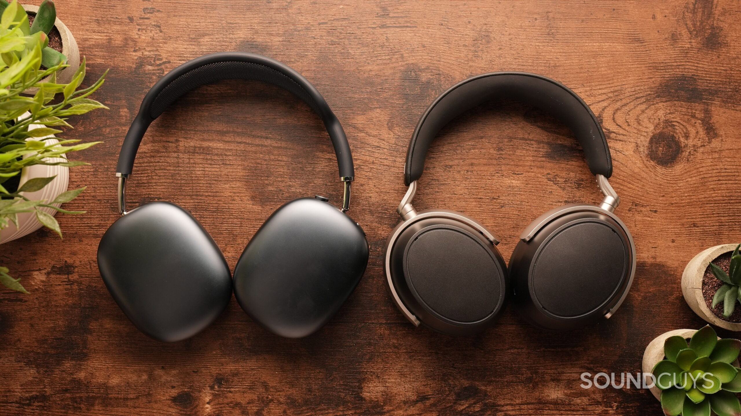 airpods-max-vs-sennheiser-hdb-630-1 The AirPods Max 2 and the Sennheiser HDB 630 sit side-by-side on a table, cups down.