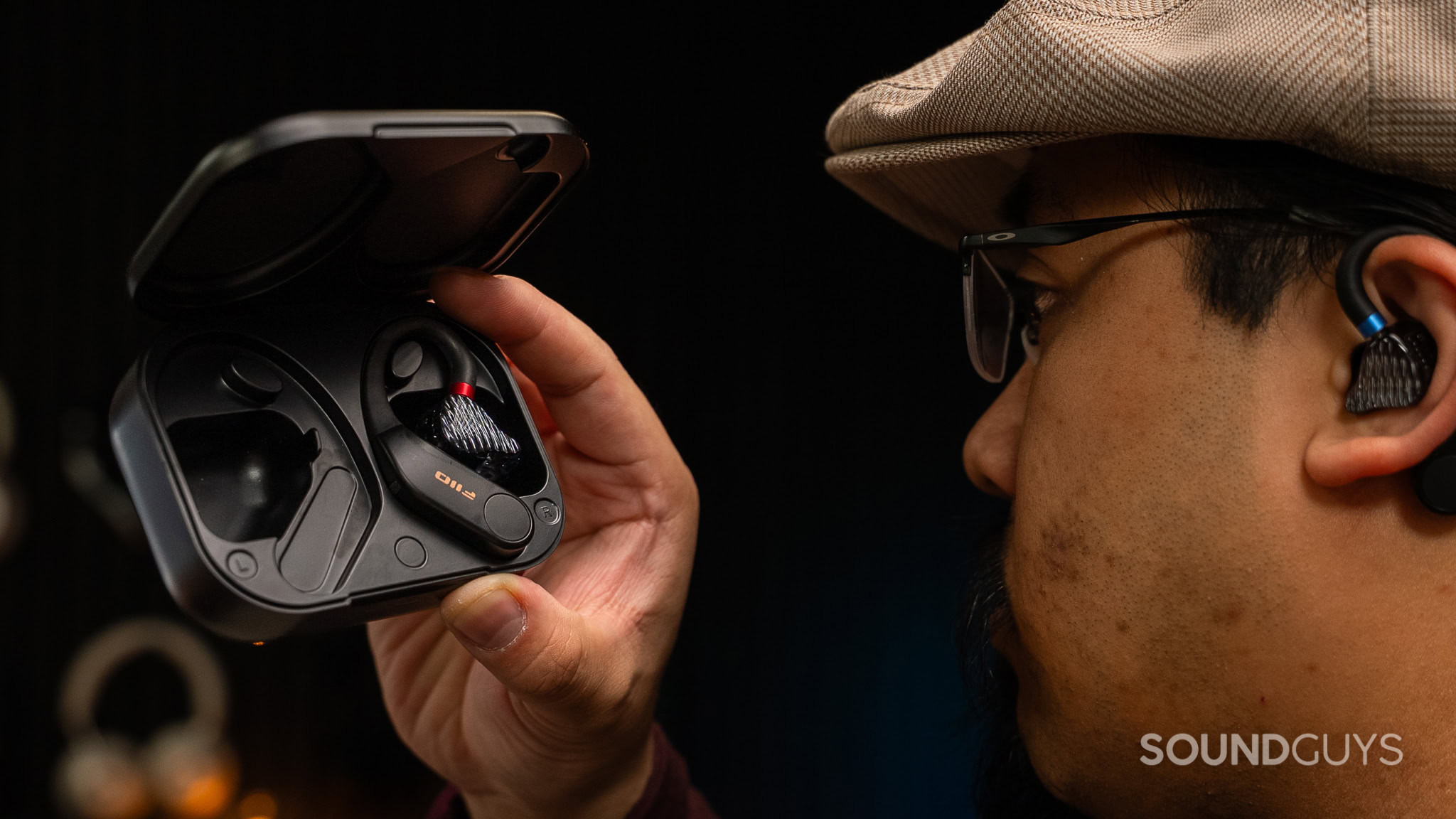 Man holding a case holding earbuds wireless adaptors.