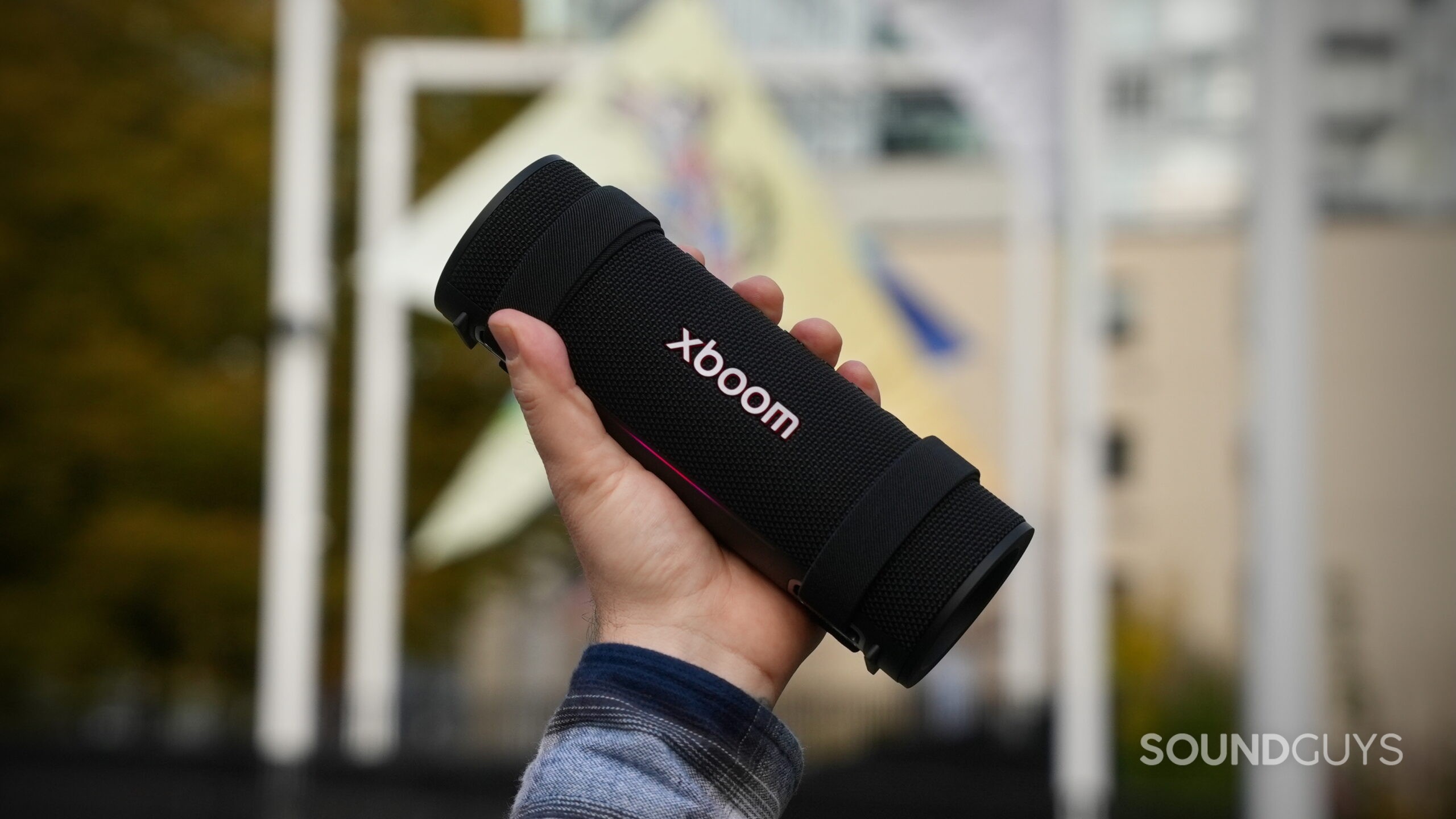 LG xboom Grab 5 a hand holding a LG xboom Grab speaker up in the air.