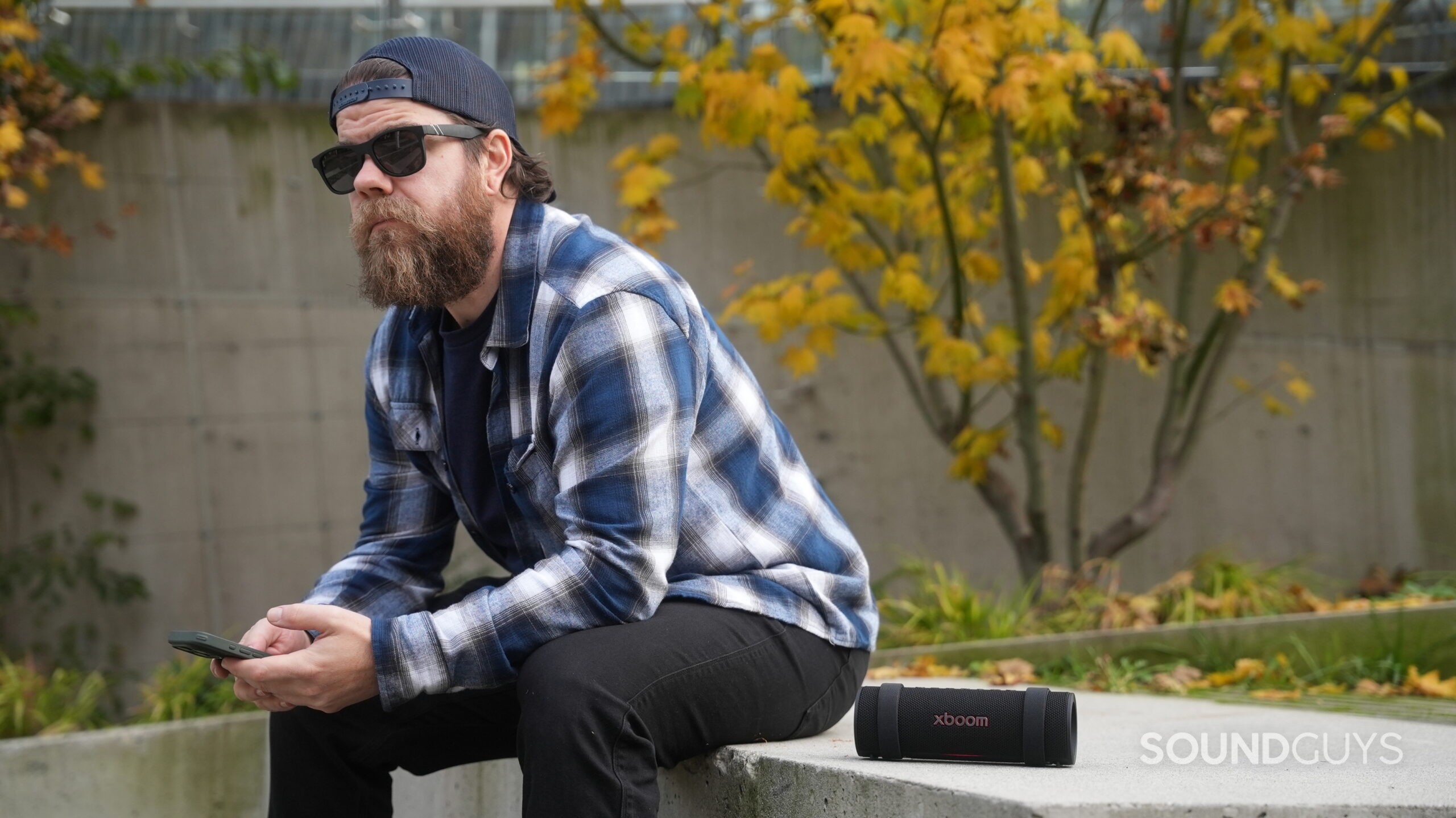 LG xboom Grab 7 An LG xboom Grab speaker placed next to a man in sitting down in the city.