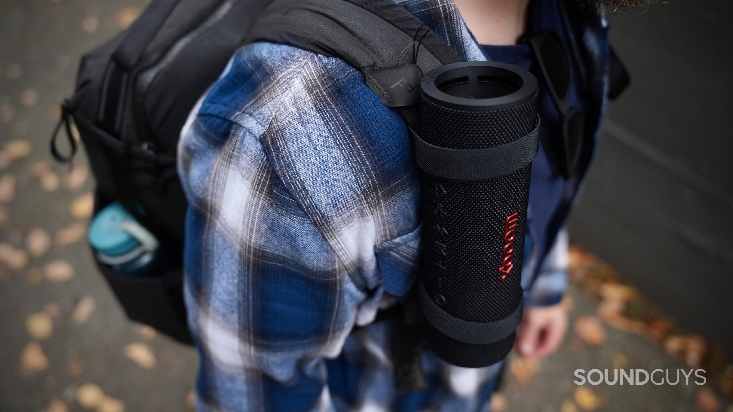 An LG xboom Grab speaker strapped to a man's backpack.