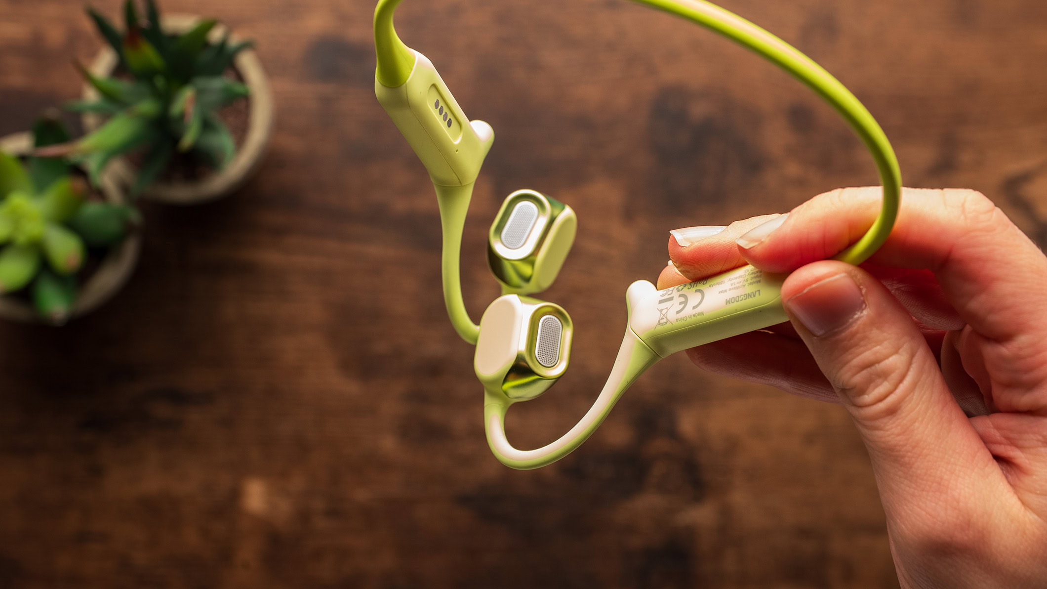 A hand holding the AirWave Max headphones.