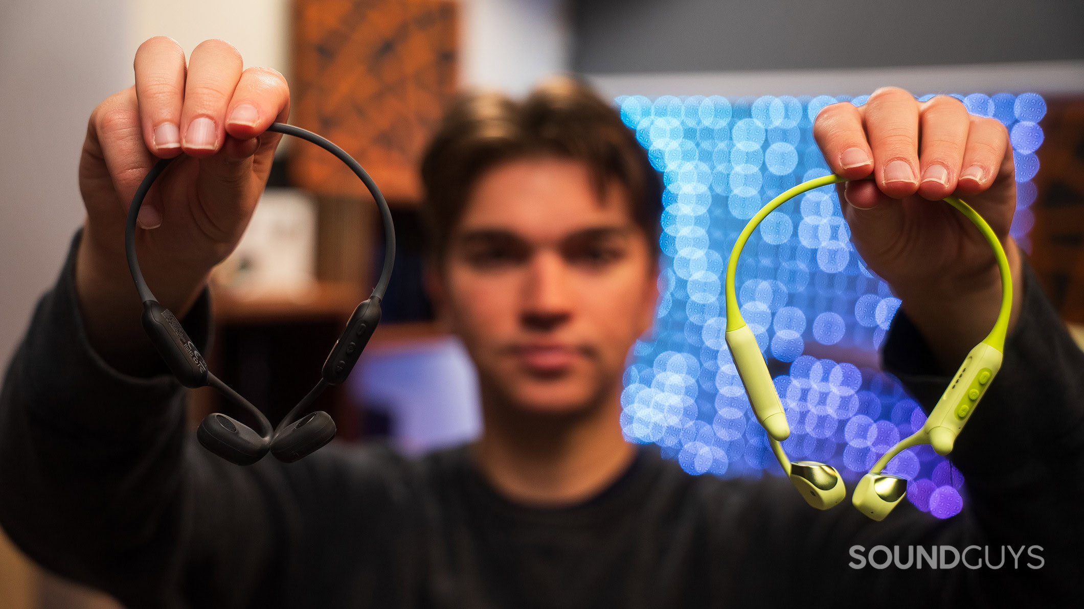 Langsdom AirWave Pro and Max held in hand A man holding the Langsdom AirWave Pro and AirWave Max headphones.