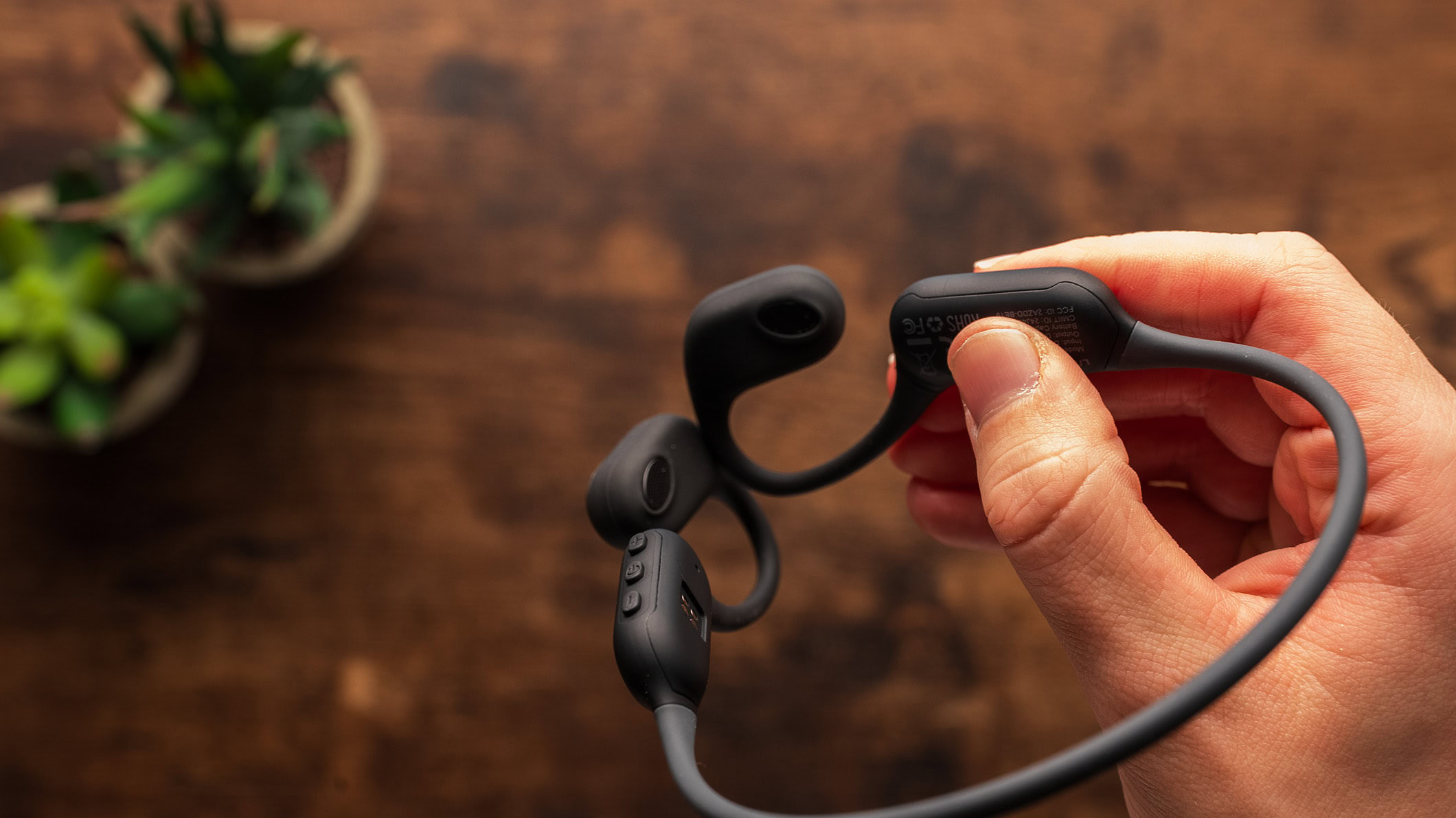 A hand holds the AirWave Pro headphones.