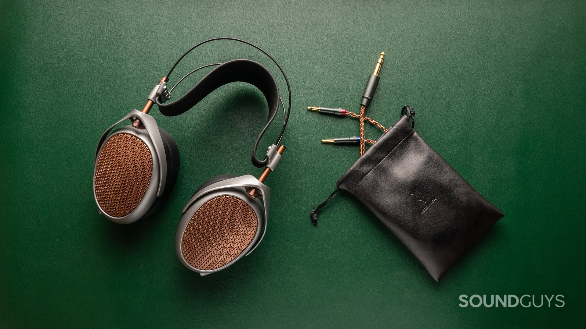 A photo of the Meze Audio Poet on a green leather desk, with the cable pouch next to it.