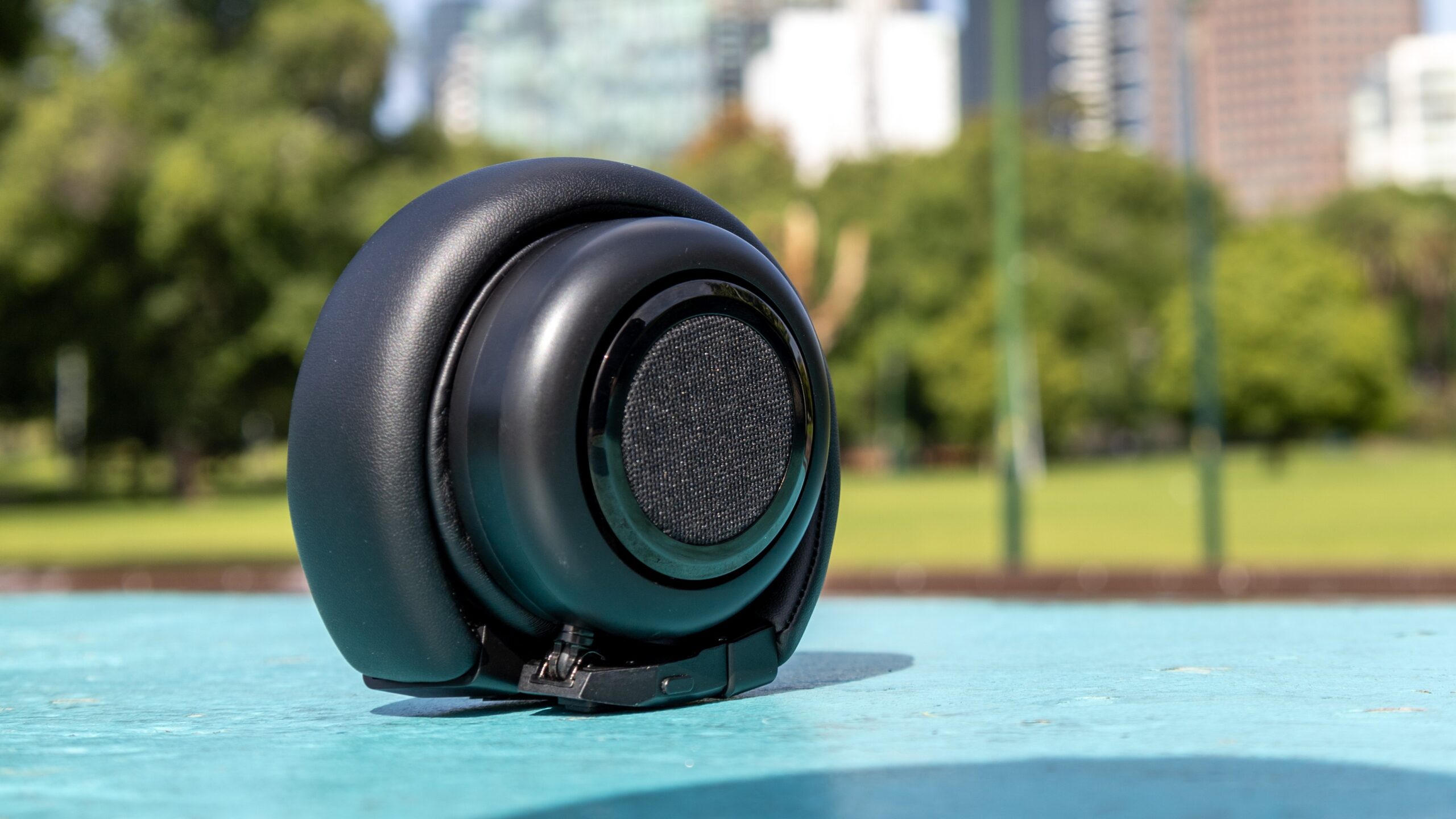 TMD Neo headphones folded in speaker mode laying on blue bench.