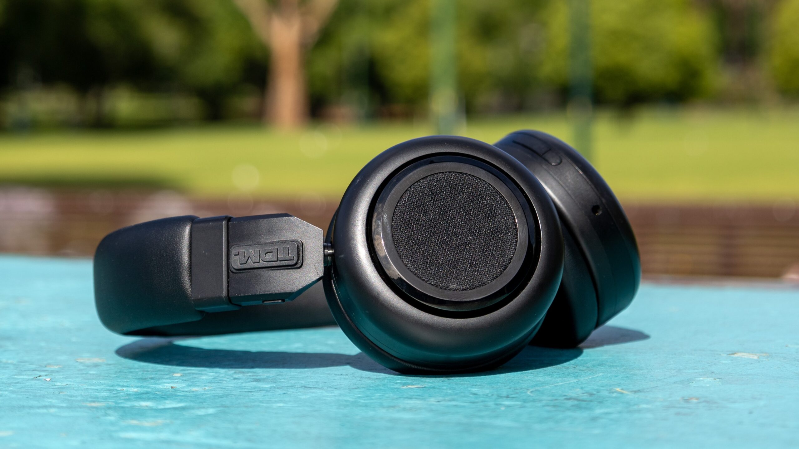 TMD Neo headphones unfolded laying on blue bench.