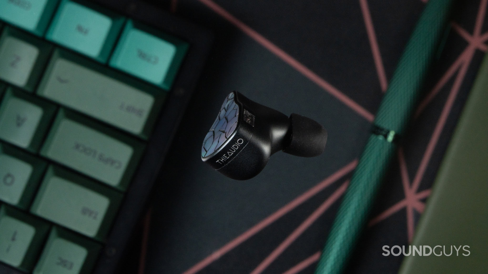 ThieAudio Hype 4 MKII Top Down Top View Close up ThieAudio Hype 4 MKII earbuds close up with from the top with a keyboard, pen and notebook in the background.