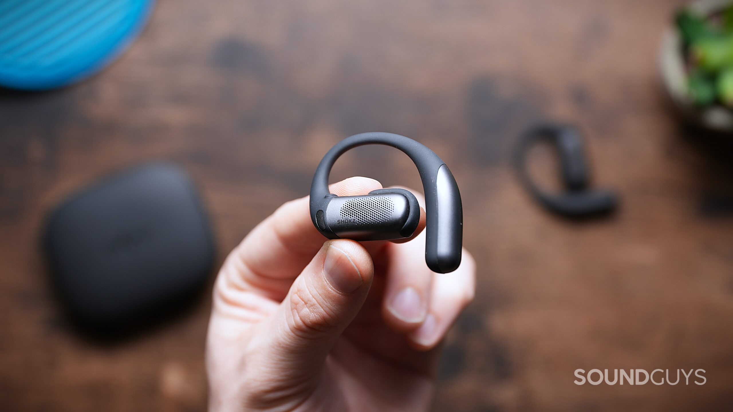 A hand holding the shoke openfit pro earbud