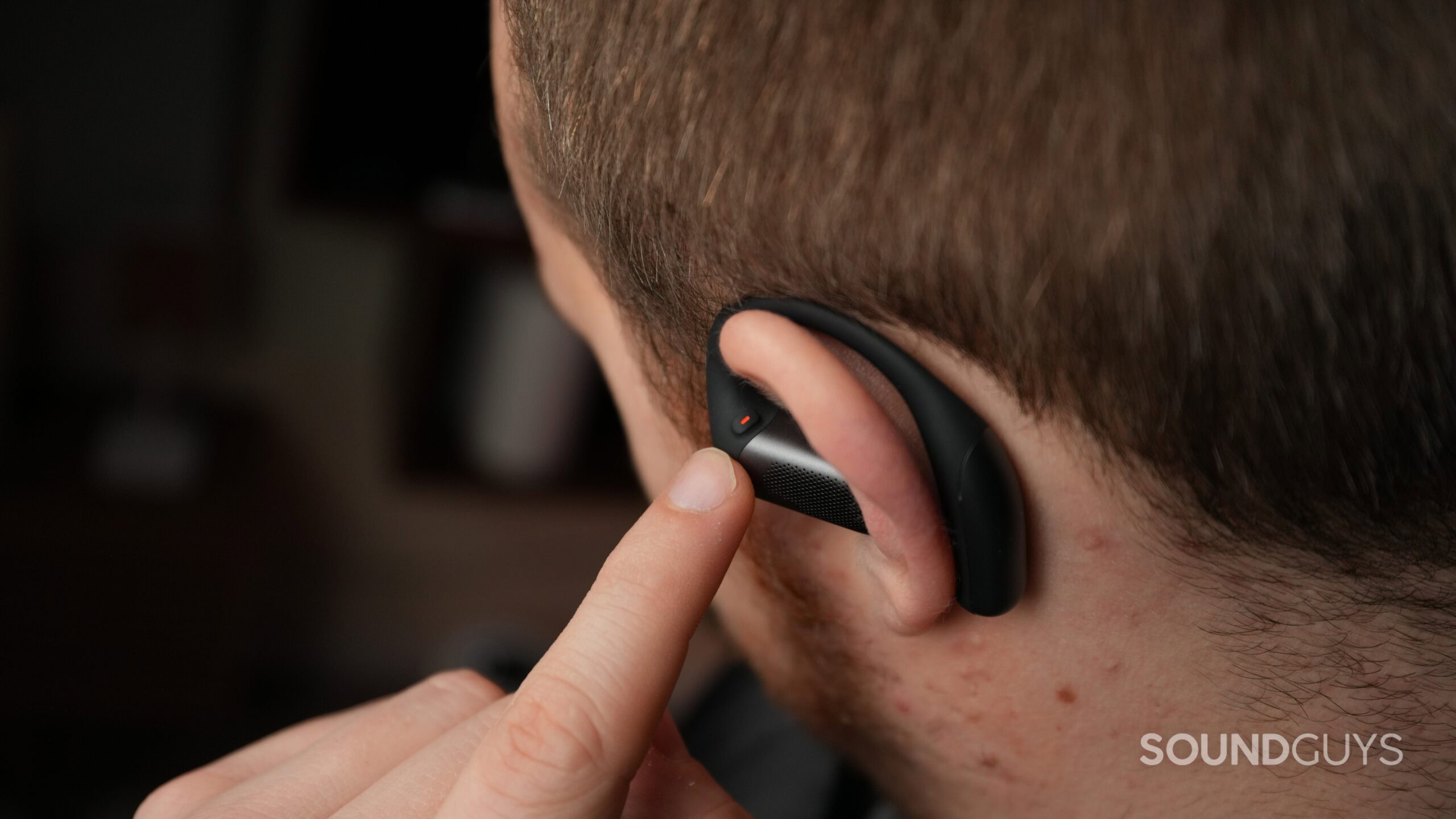 a man wearing the shokz openfit pro and pointing to the controls