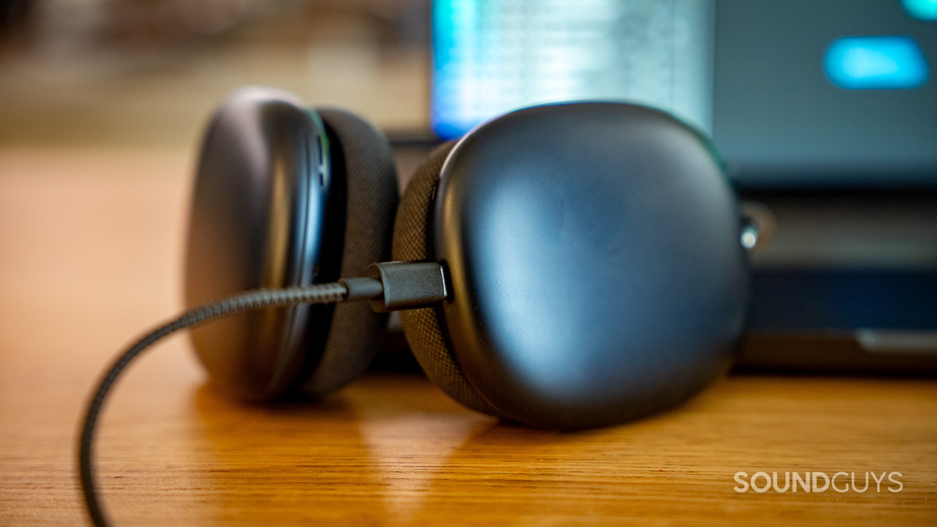 AirPods Max USB-C port cable plugged in close-up AirPods Max with USB-C lying on table in front of laptop with a USB-C cable pluuged in