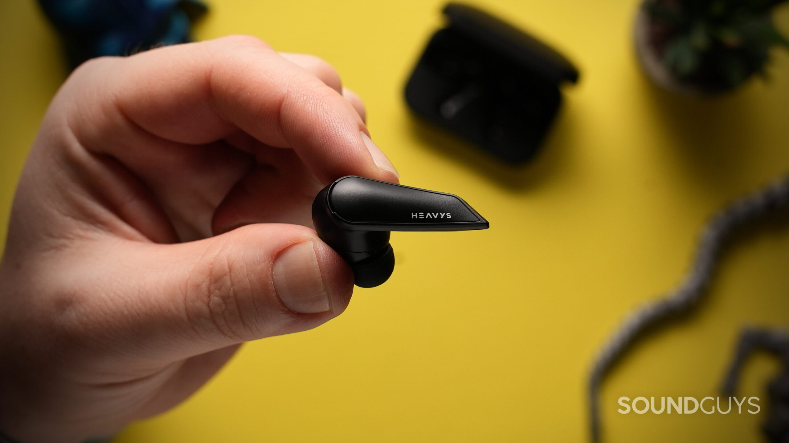 Top down photo of a hand holding a single Heavys H1E earbud.
