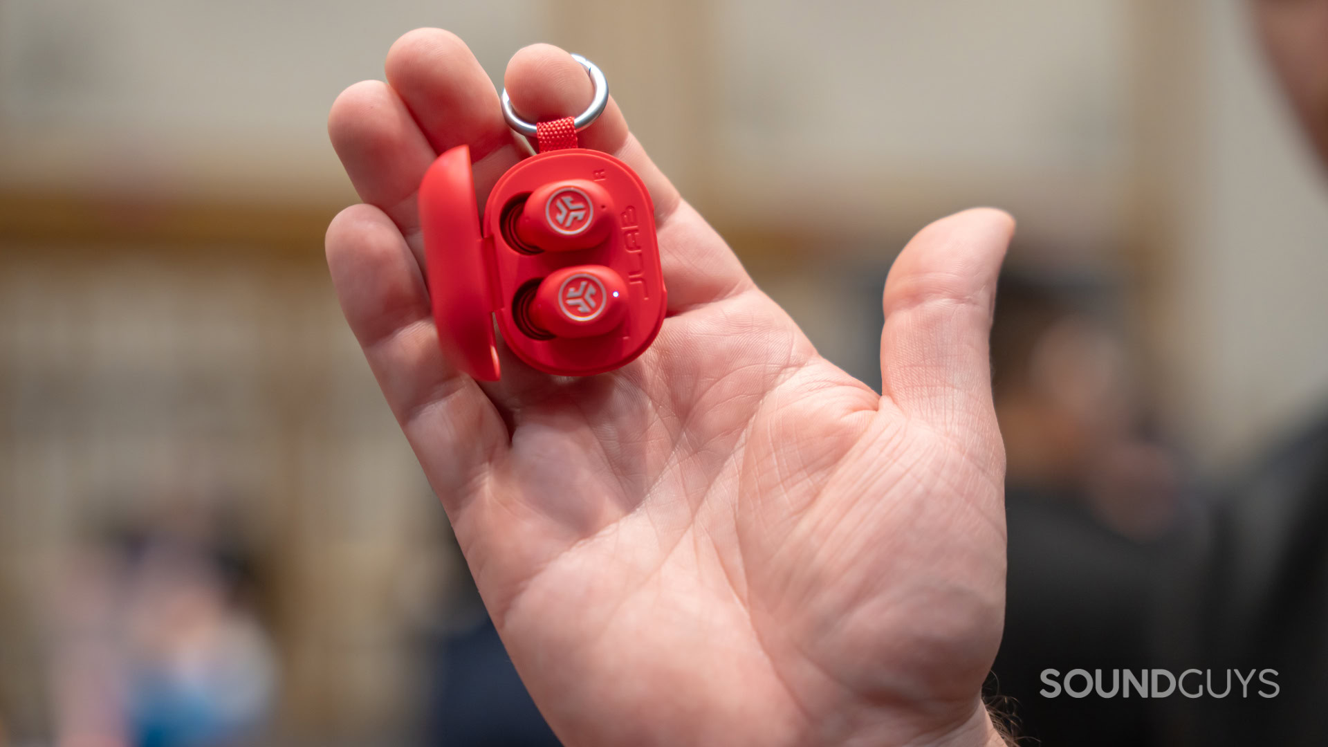 hand holding jlab jbuds mini, red, with key attached