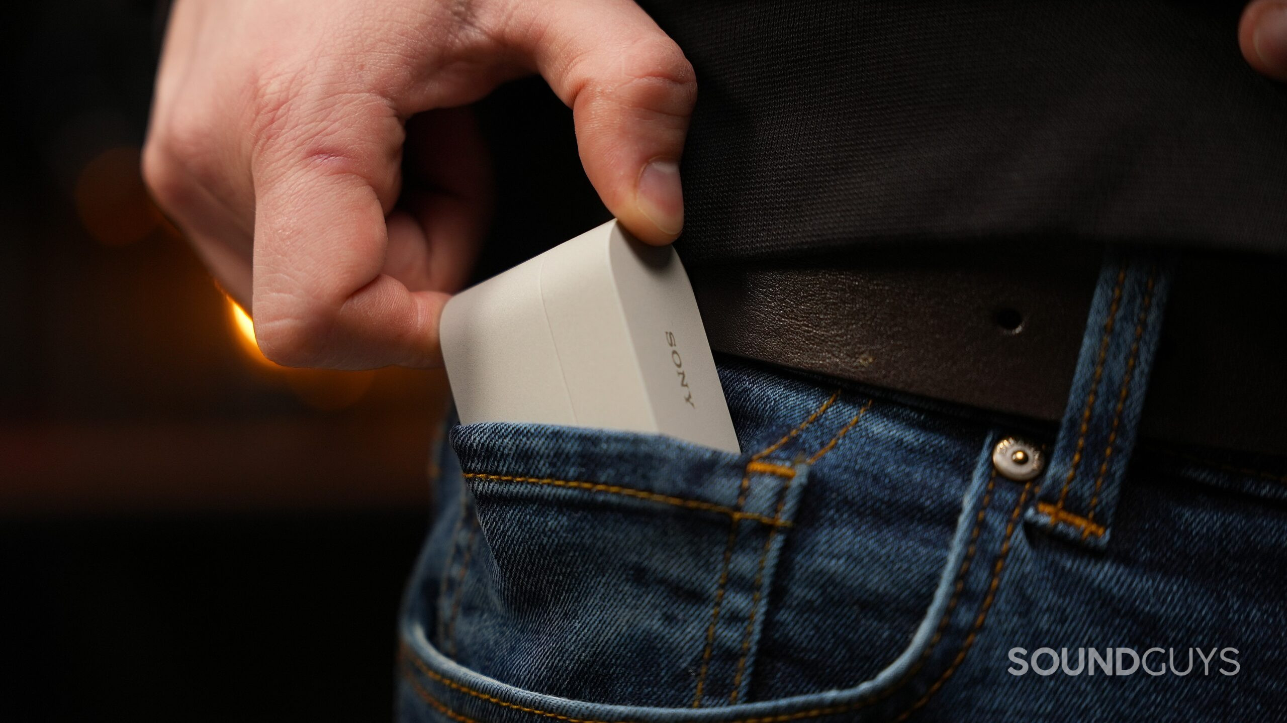 a hand putting the sony wf-100xm6 earbuds into pants pockets