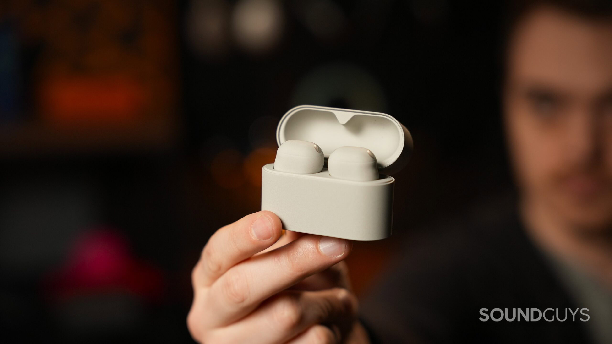 Holding the Sony WF-1000XM6 earbuds in case A person holding the Sony WF-1000XM6 earbuds in case