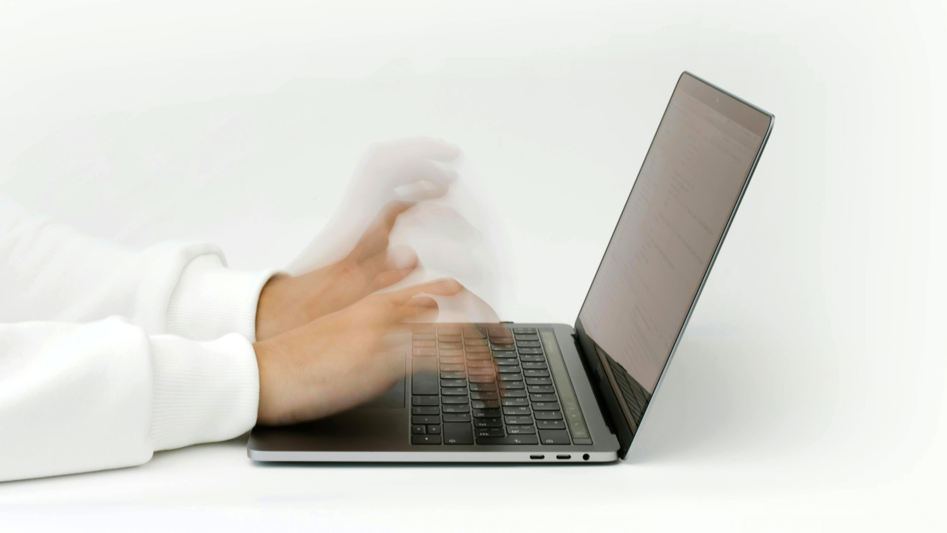 A photo of someone typing on a laptop so fast that the fingers are a blur.