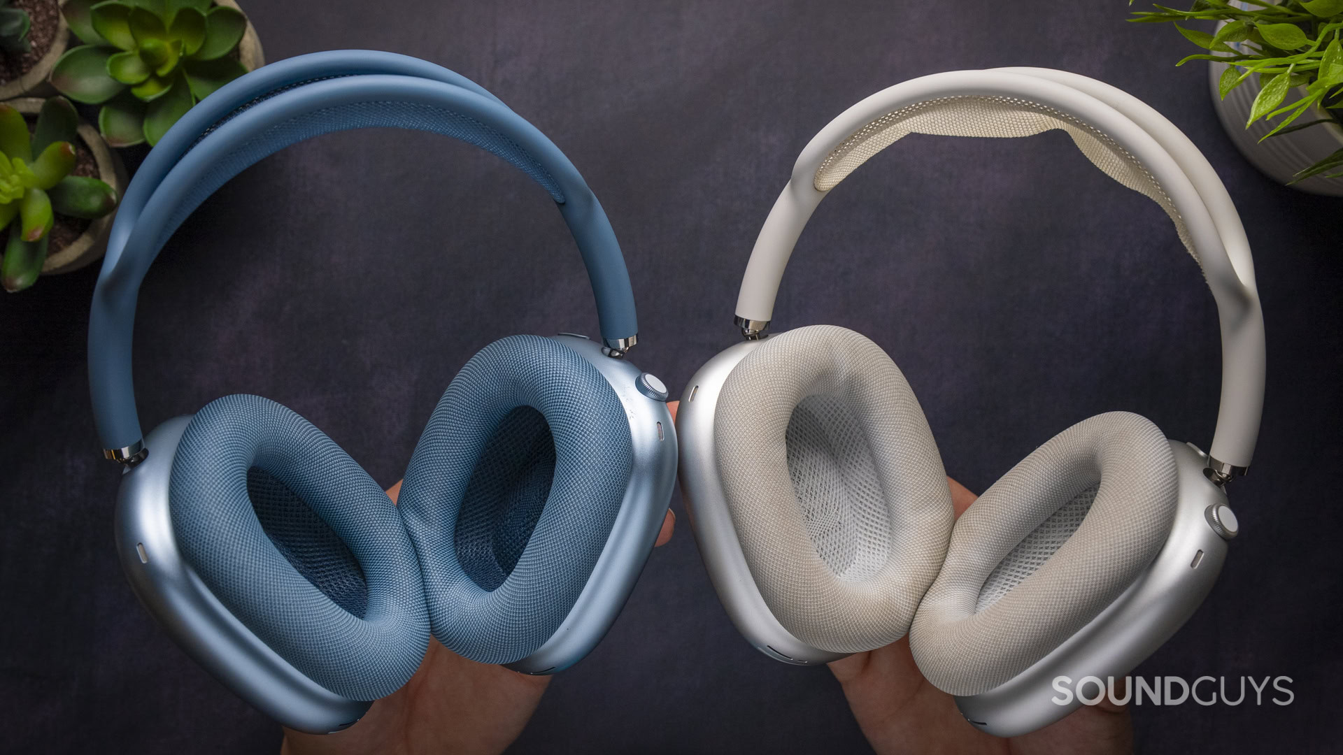 Apple AirPods Max 2 vs Apple AirPods Max 1-7 Apple AirPods Max 2 in blue (left) and AirPods Max 1 in silver (right) held in hands with ear cushions facing forward.