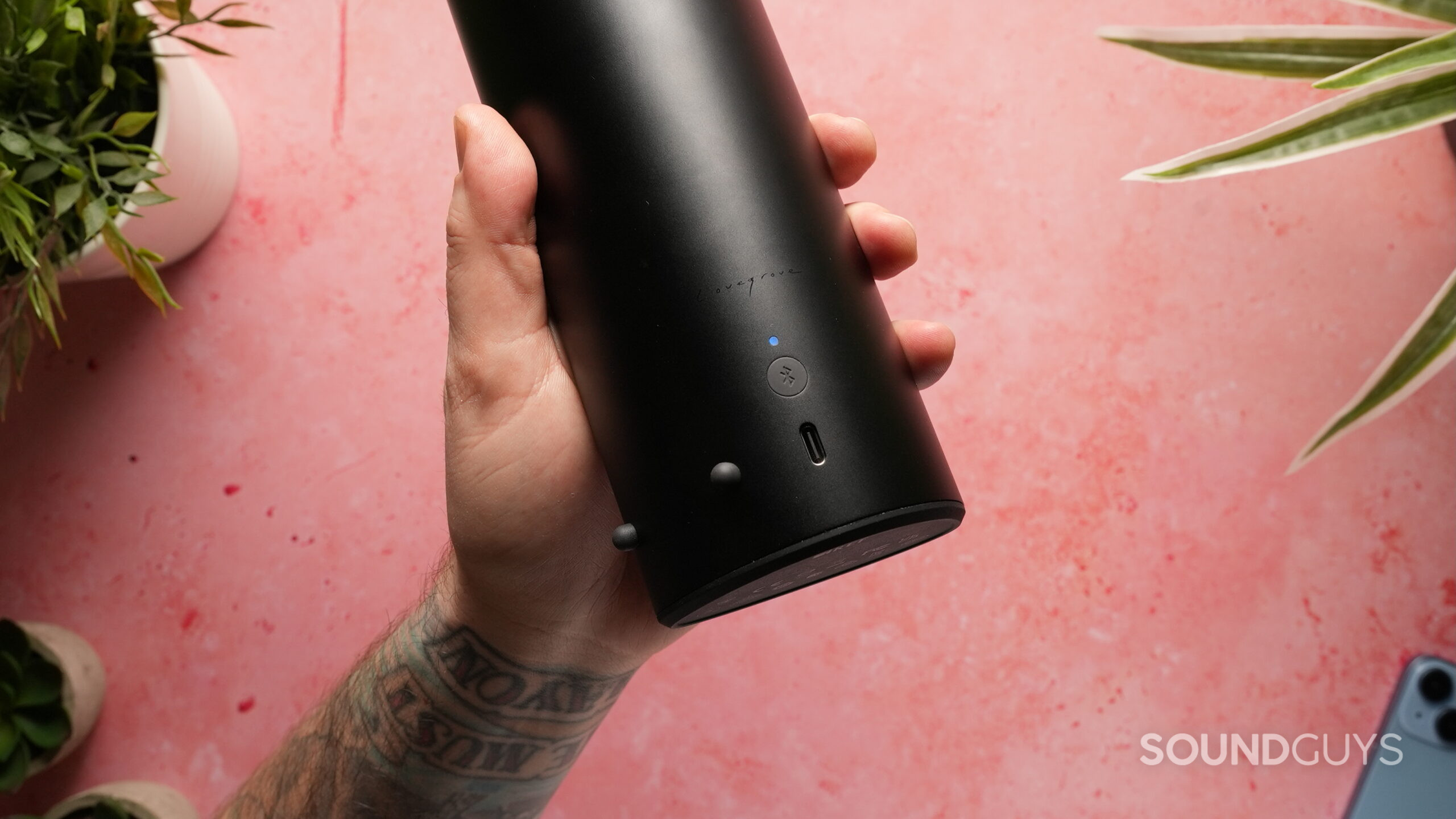 KEF Muo - 4 The KEF Muo Bluetooth speaker in black held in a hand showing the rear controls and USB-C charging port.