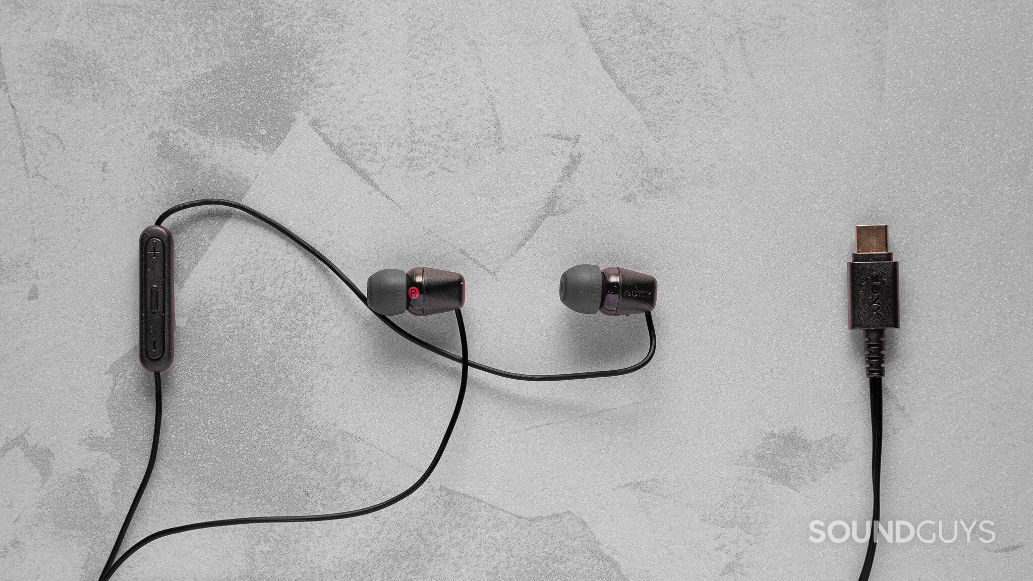 Sony IER-EX15C earbuds laid flat on a surface with USB-C connector and inline remote visible.