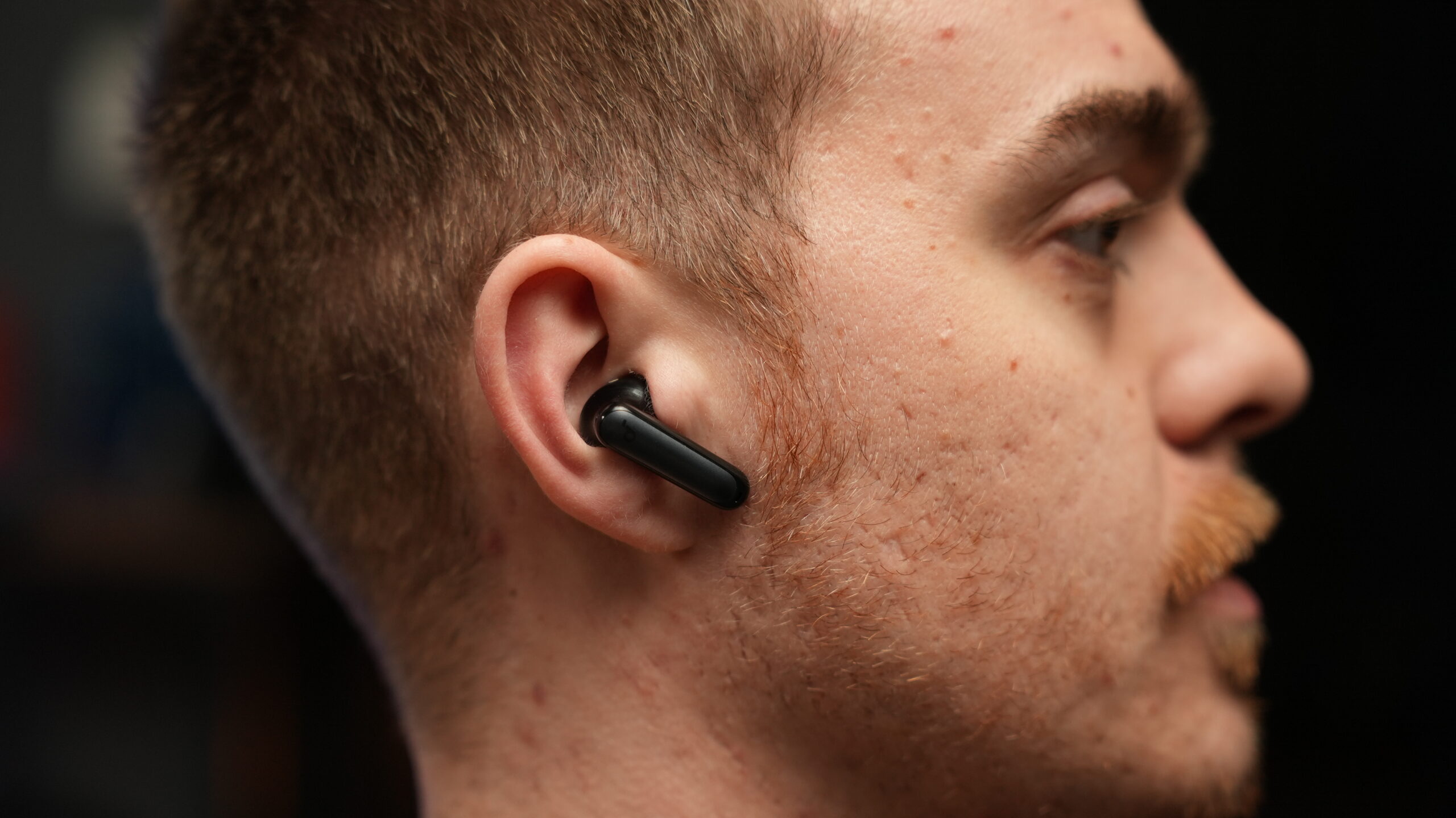 man wearing the soundcore p40i earbuds Man wearing black Soundcore P40i wireless earbuds in ear, close-up side profile.