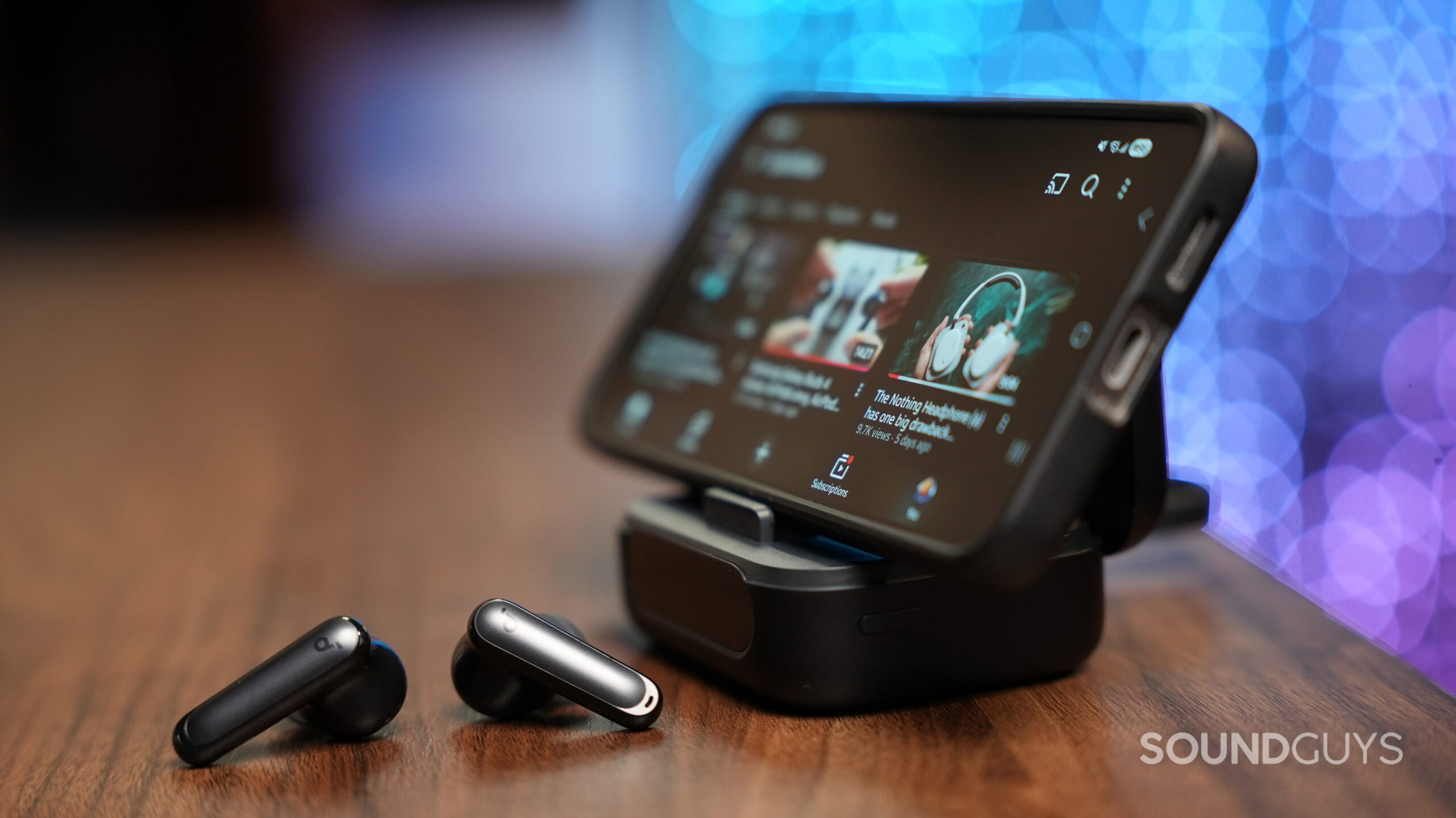 soundcore p40i earbuds Pair of Soundcore P41i true wireless earbuds placed on a wooden surface in front of a smartphone on a case stand.