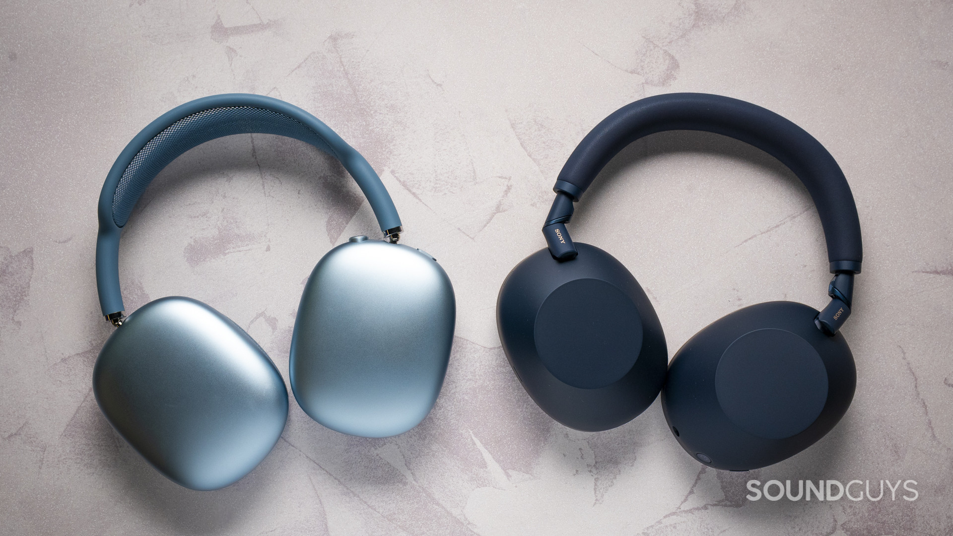 Apple AirPods Max 2 vs Sony WH-1000XM6-1 Apple AirPods Max 2 and Sony WH-1000XM6 headphones side by side on a table, showing outer earcup design.