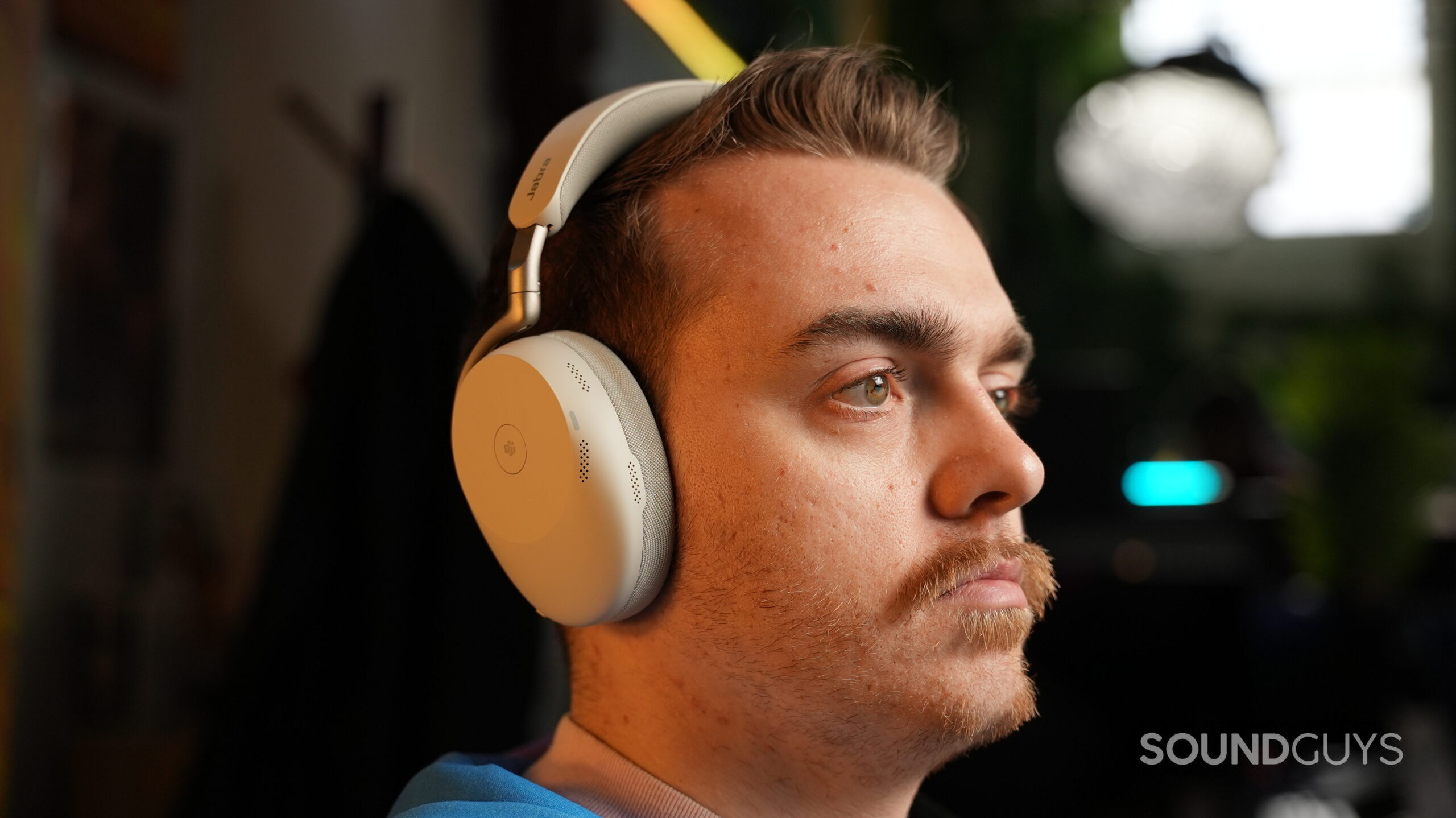 DSC09451 Person wearing Jabra Evolve3 85 white over-ear headphones, shown in side profile with a softly lit indoor background.