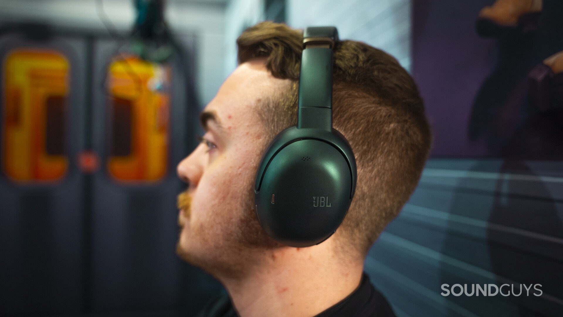 JBL Tour One M3 - 80th Anniversary Edition-8 Person wearing green JBL over-ear headphones, side profile showing ear cup design and matte metallic finish.