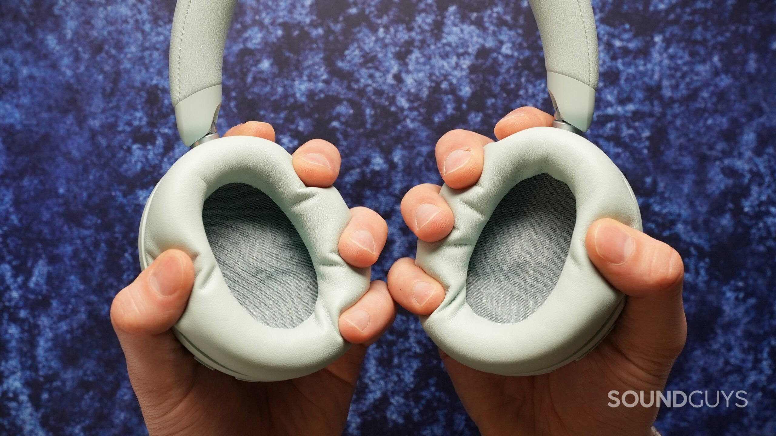 anker soundcore space 2 ear cushions Hands pressing the soft ear cushions of the Soundcore Space 2, demonstrating padding and flexibility.