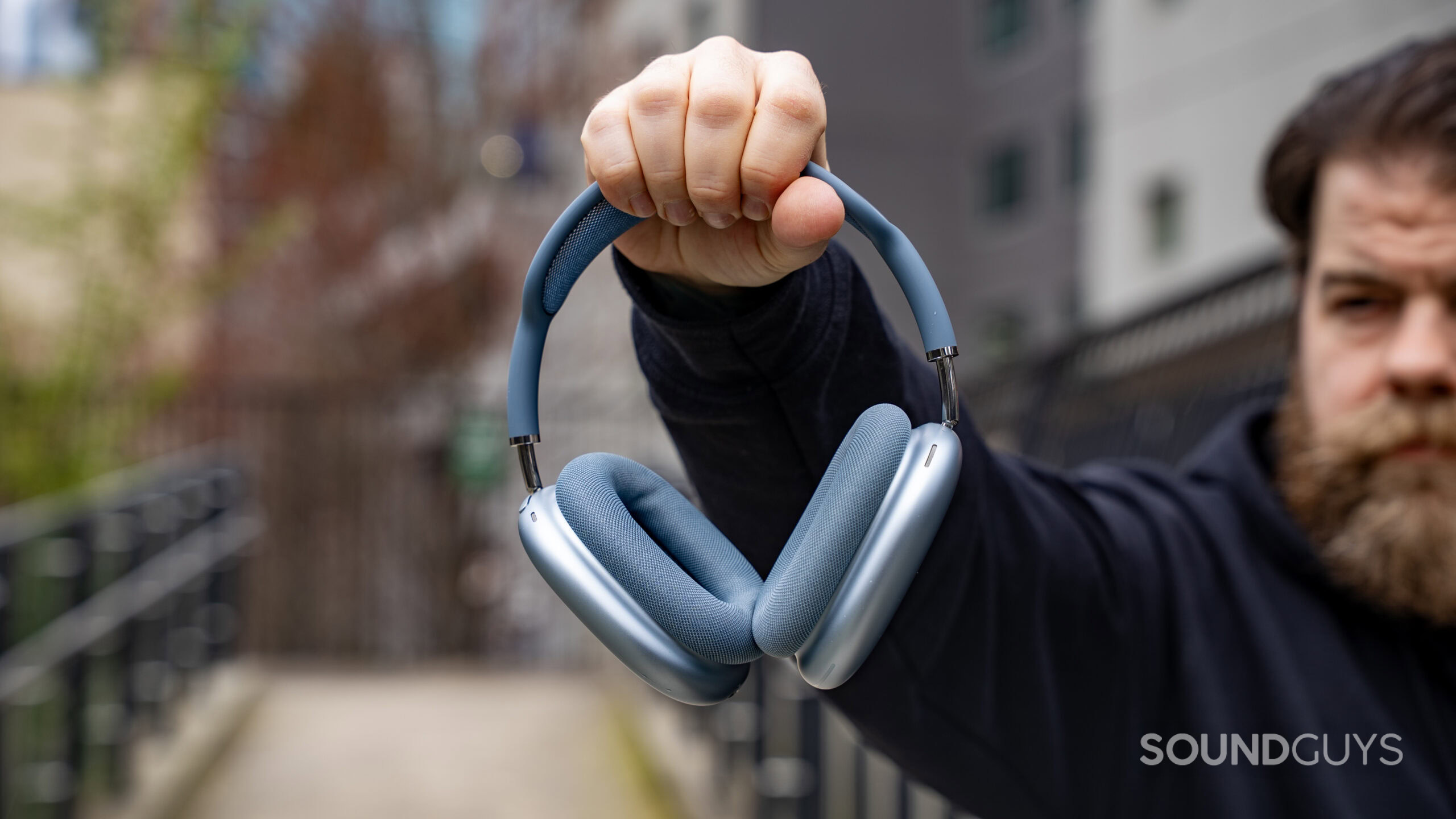 Apple AirPods Max 2 headphones in a man's hand who is holding the headphones in the air