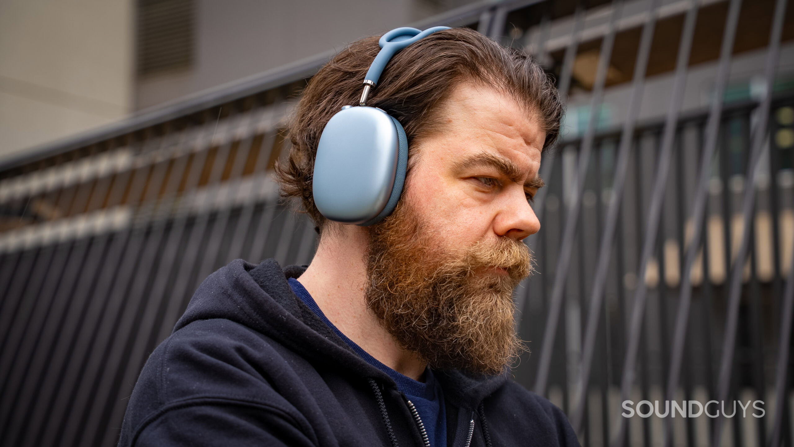 apple airpods max 2 man wearing looking down at phone A man wearing the Apple AirPods Max 2 headphones looking down.