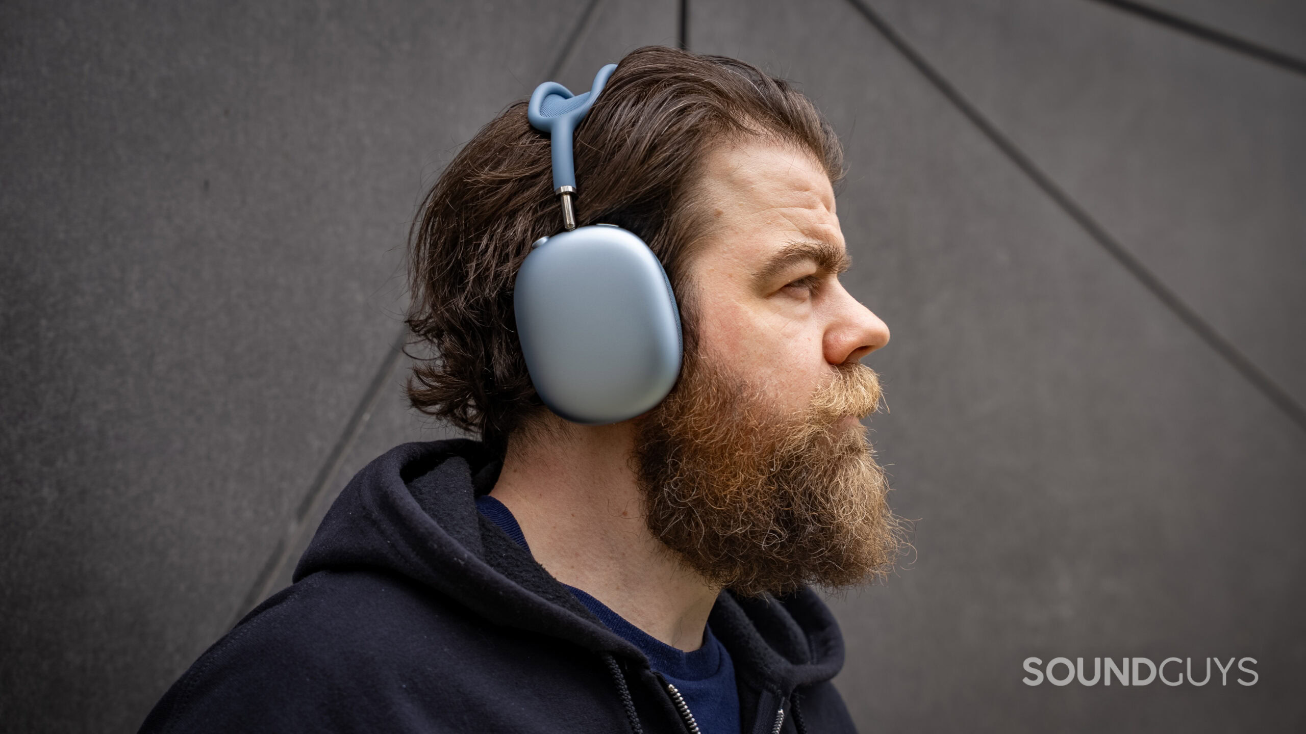 A man looks in the distance wearing the Apple AirPods Max 2 headphones