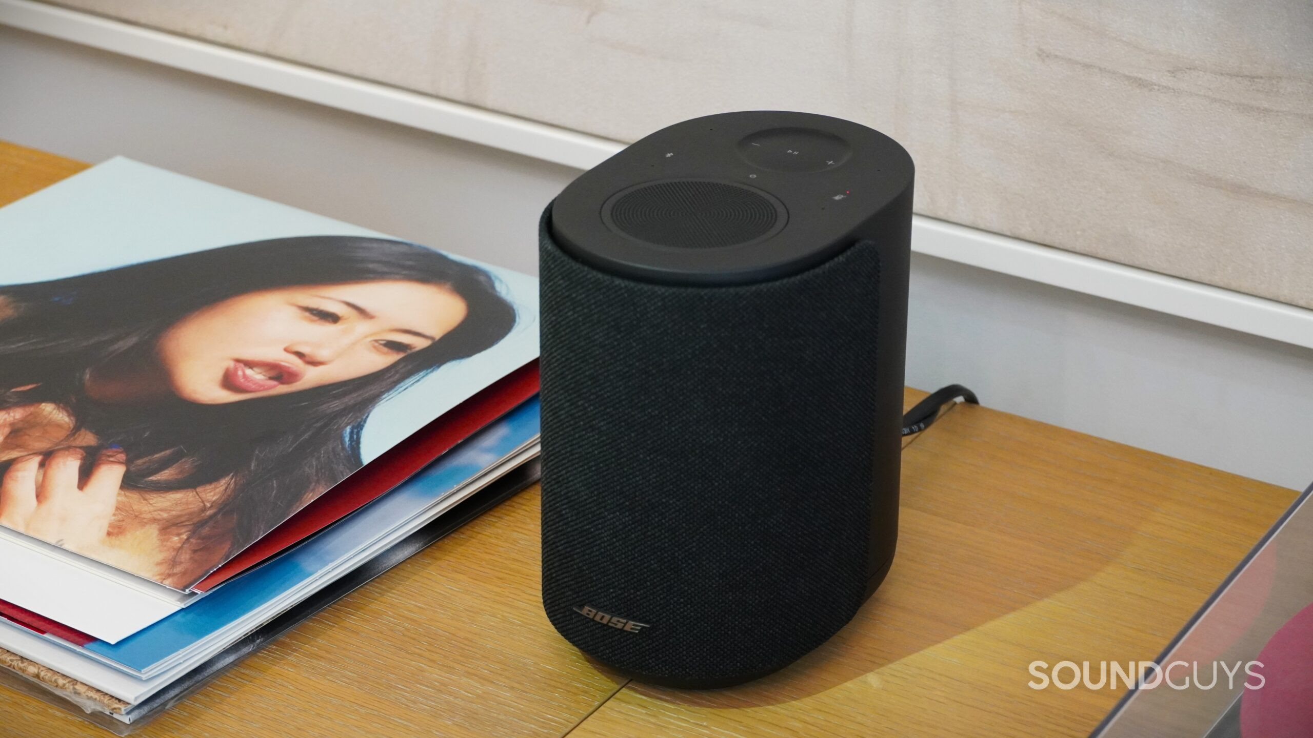 Angled top view of a black Bose smart speaker showing touch controls and fabric grille.