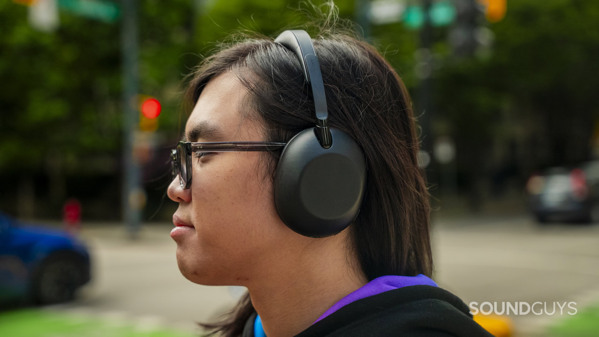 A long-haired man listens to the Sony 1000X The Collexion on the street.