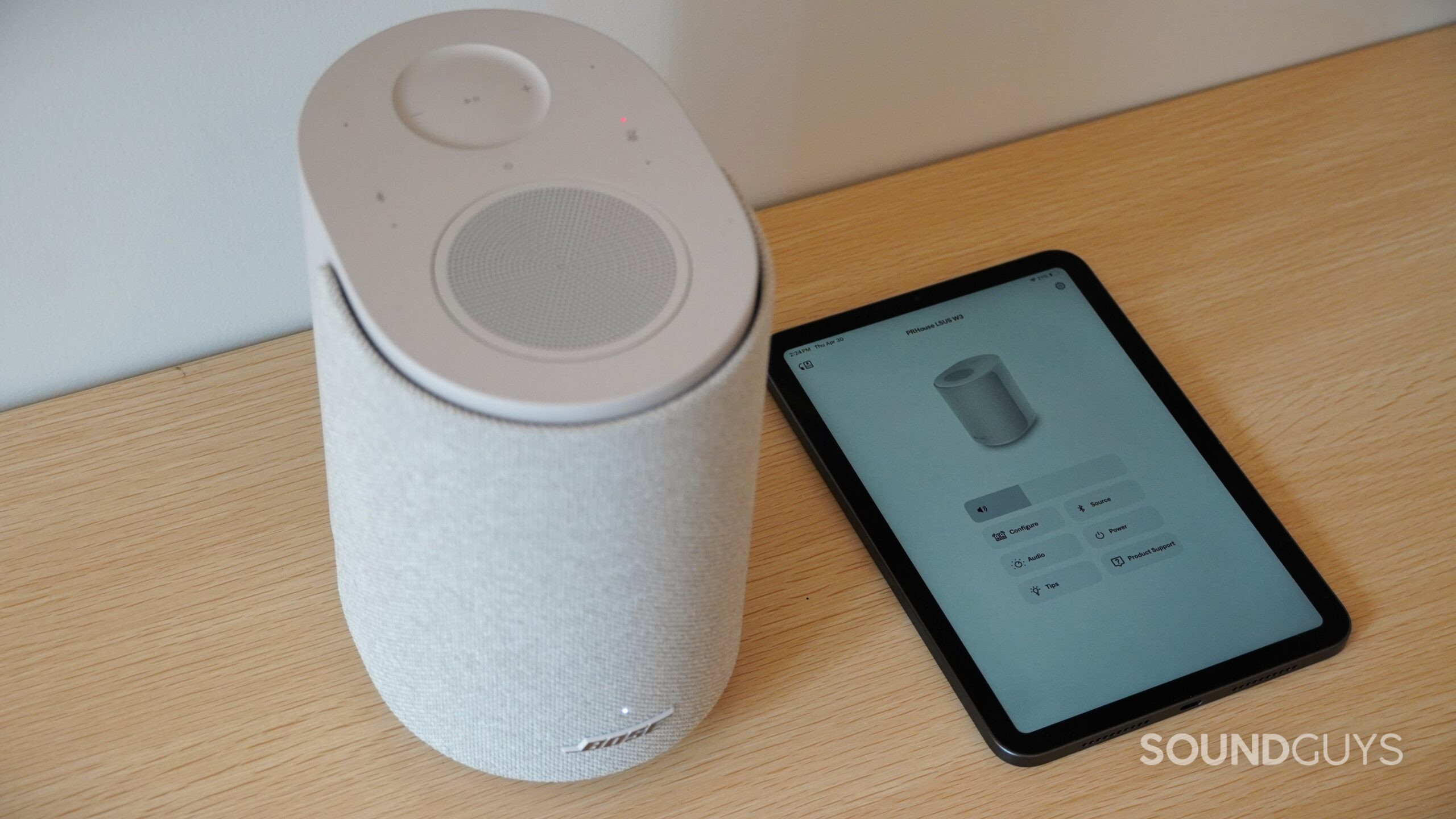bose speaker with ipad Bose smart speaker next to a tablet displaying the Bose app control interface.