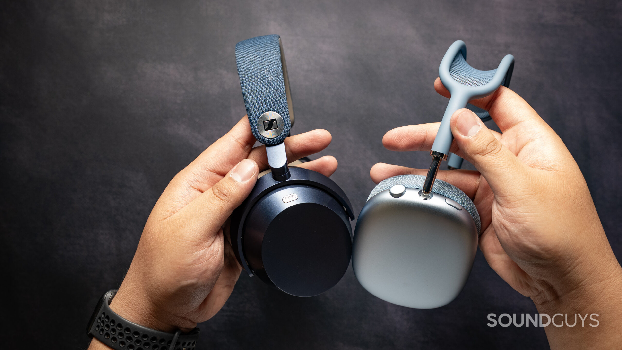 sennheiser momentum 5 wireless headphones vs. apple airpods max 2_side view holding 2 Top down photo of the Sennheiser Momentum 5 Wireless headphones next to the AirPods Max 2, showing their outter ear cups.