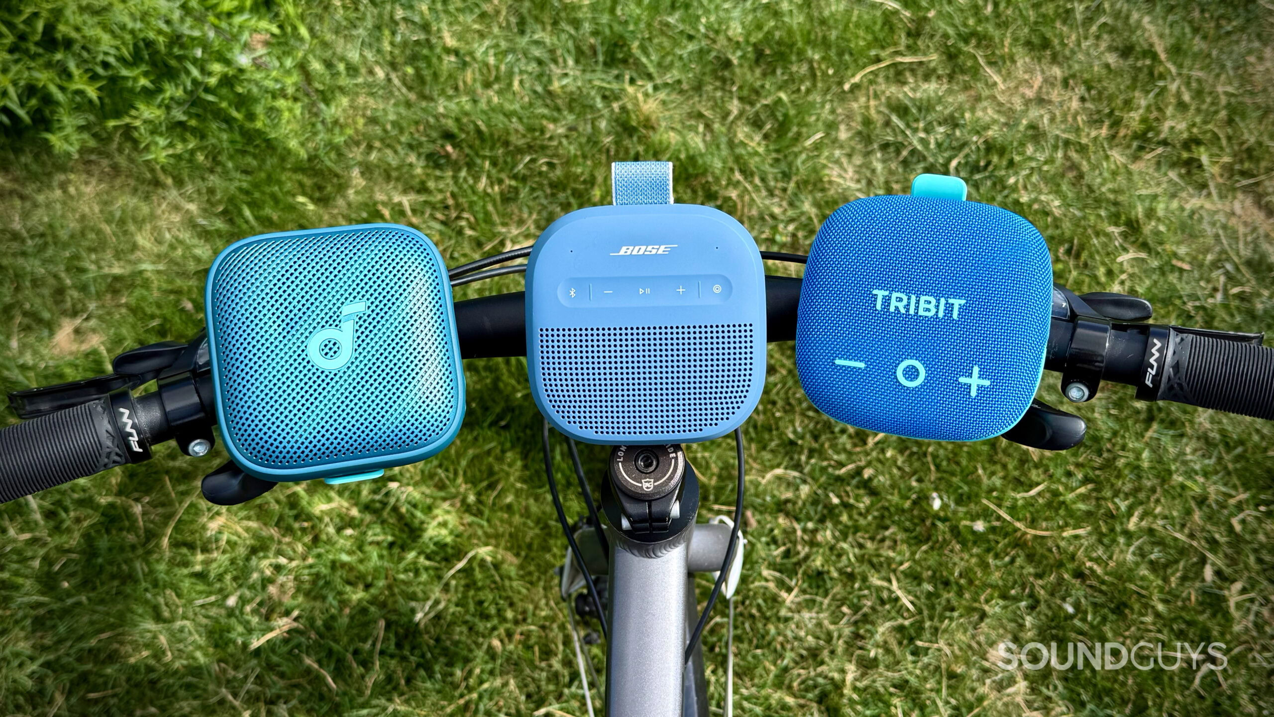 Bose SoundLink Micro (2nd Gen) alternatives - 1 (2) The Soundcore Boom Go 3i, Bose SoundLink Micro (2nd Gen), and Tribit StormBox Micro 3 attached to bicycle handlebars.