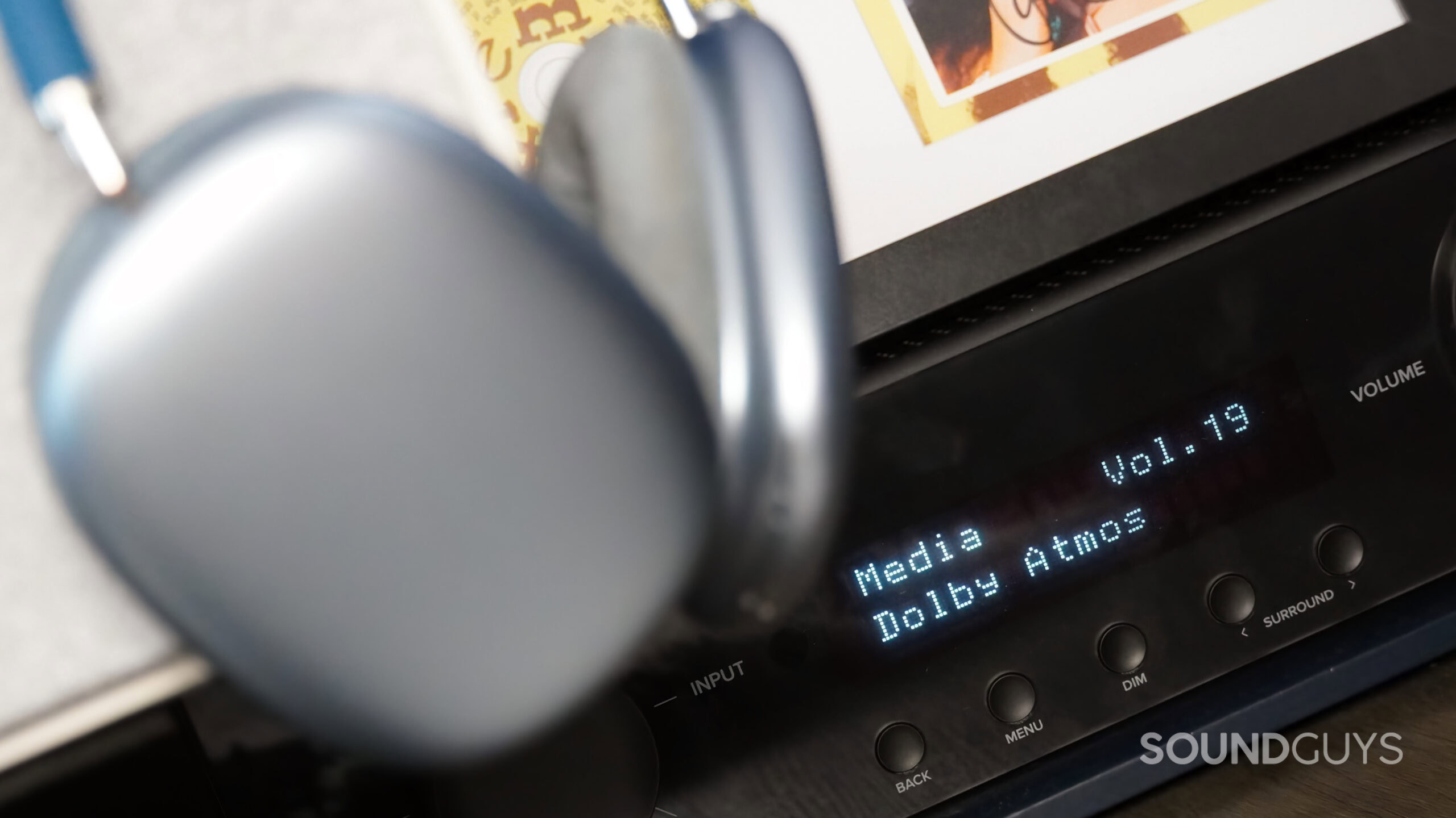 A Dolby Atmos receiver in focus with AirPods Max in the frame.
