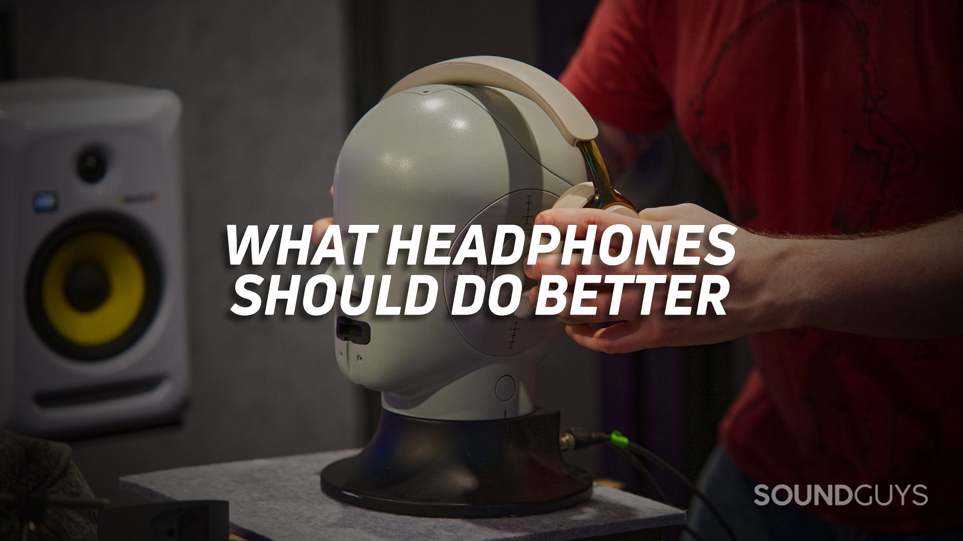 WHAT-HEADPHONES-SHOULD-DO-BETTER-HERO A photo of a man putting a set of headphones on a test head, with the text "what headphones should do better" overlaid.