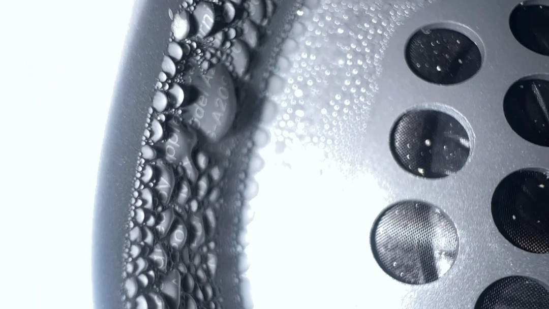airpods max condensation close up Extreme close-up of condensation inside an Apple AirPods Max ear cup, highlighting dense water droplets forming along the interior wall beside the speaker grille.