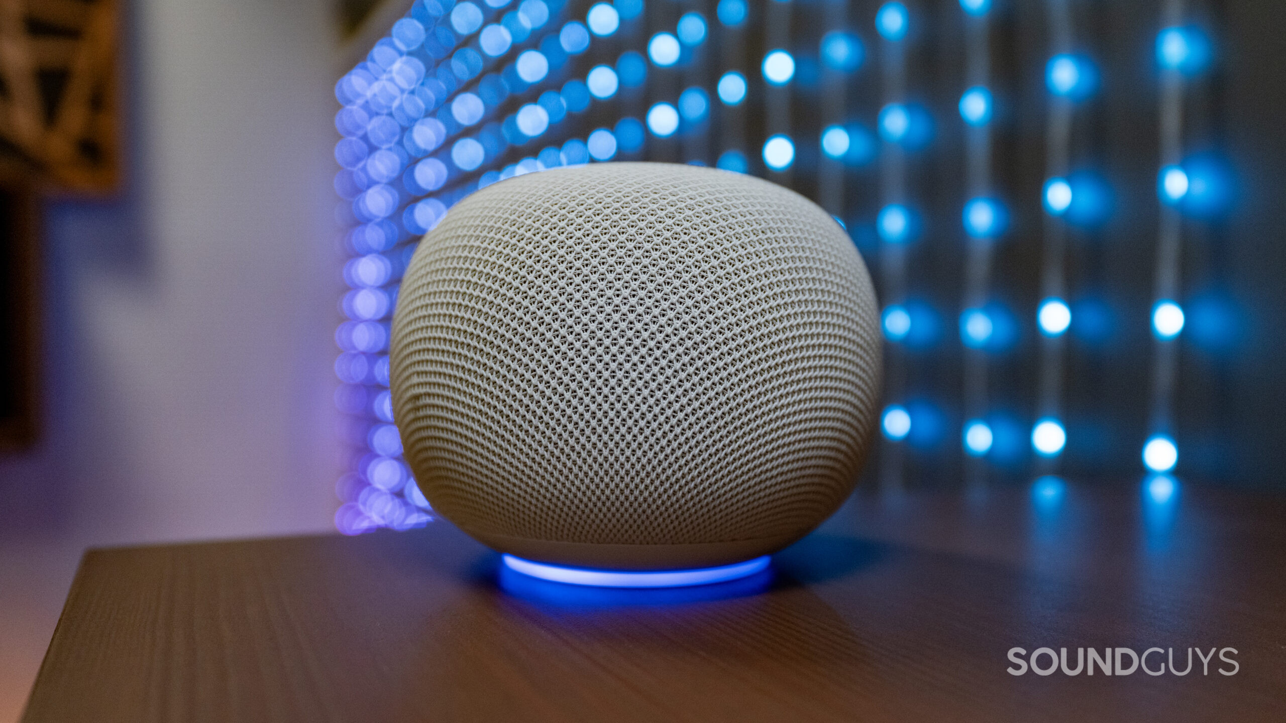 google home speaker with ring light activated, sitting on a table, with blue lights led in background