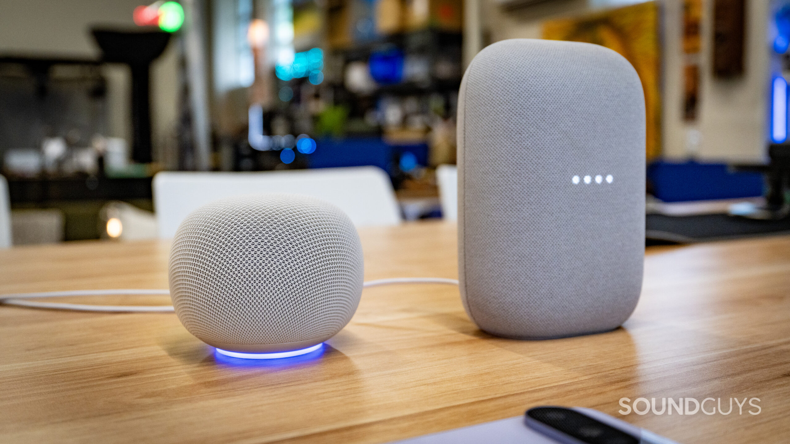 google home speaker beside google nest audio on a wooden table