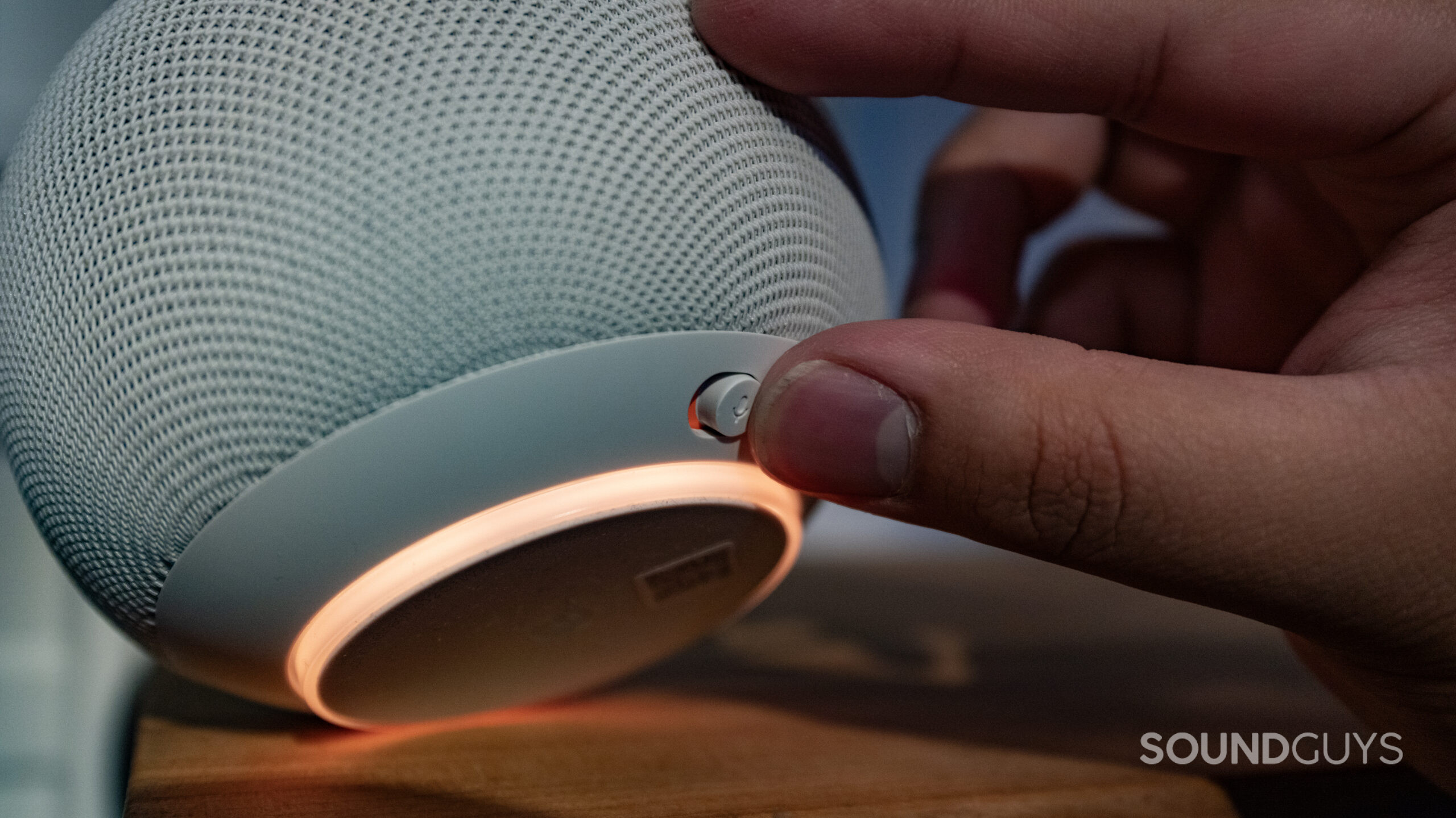 a hand activating the mic mute switch underneath the google home speaker