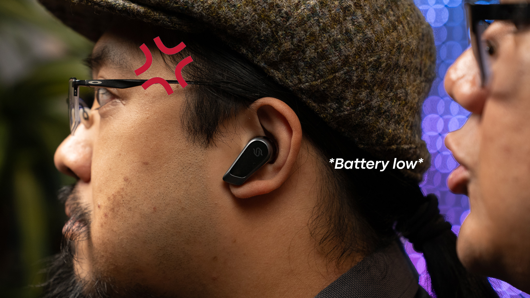 Man wearing earbud being whispered that the battery is low