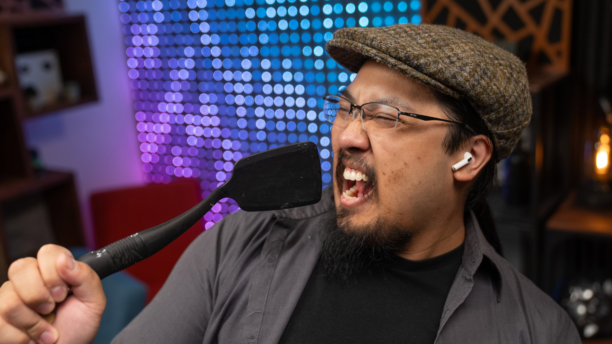 Man singing into spatula wearing earbuds