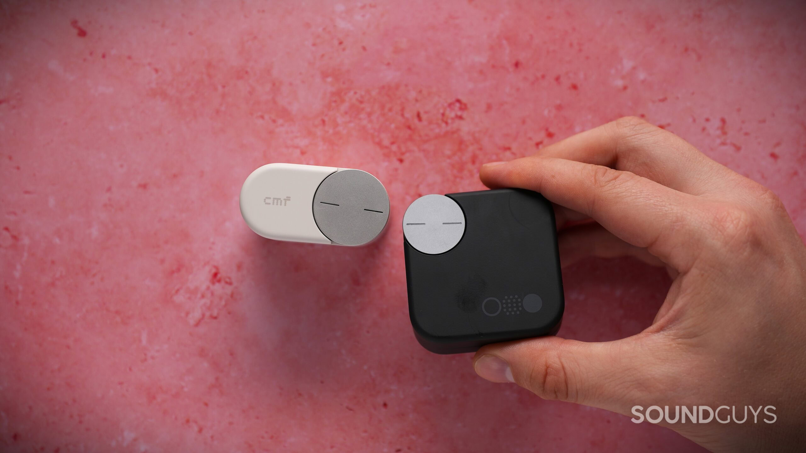 CMF Clip Pro smart dial comparision The CMF Clip Pro case beside a black CMF charging case, highlighting the different sizes and Smart Dial designs.