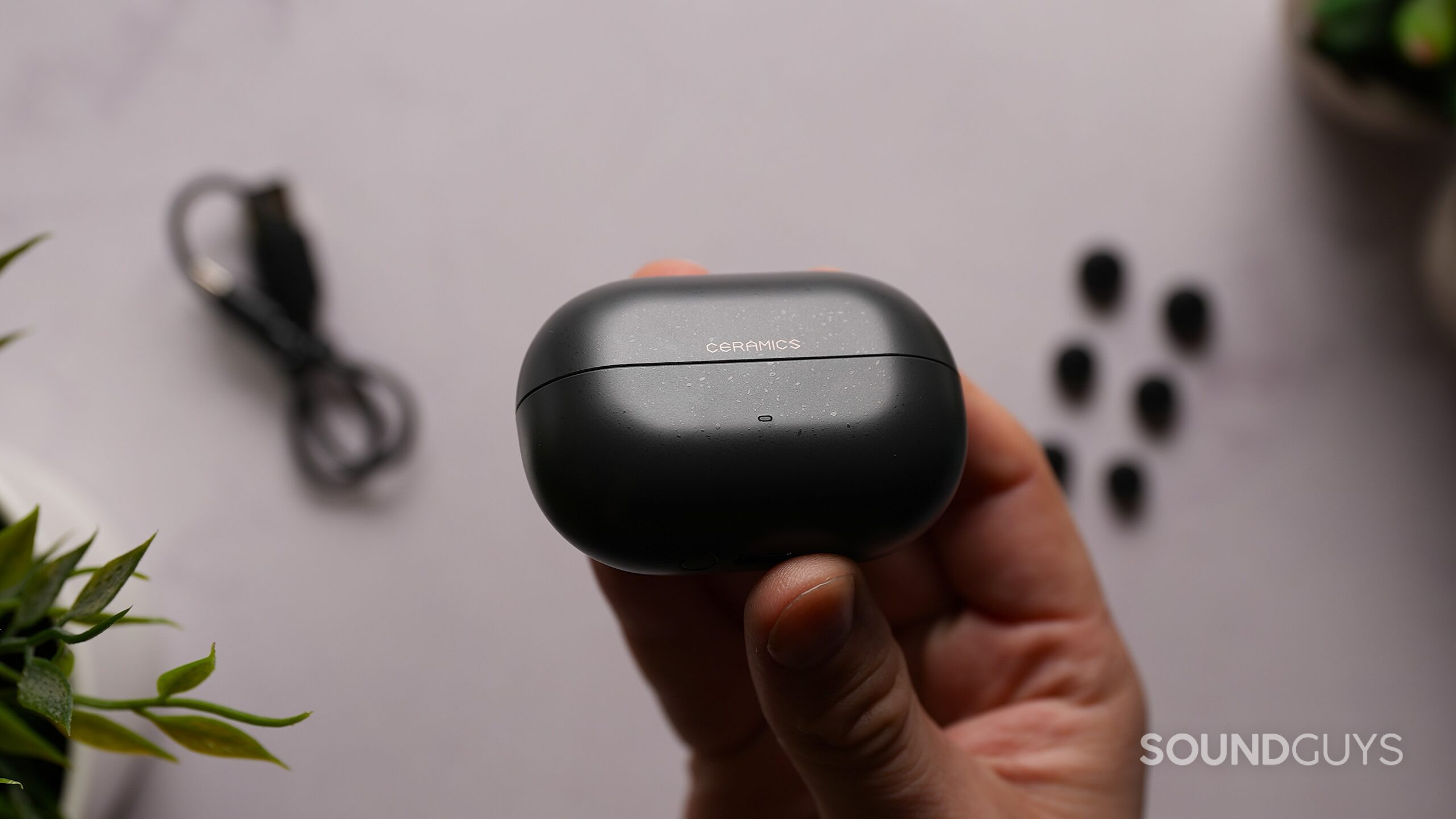 Close-up of the closed black ROSESELSA Ceramics Ultra charging case held in one hand.