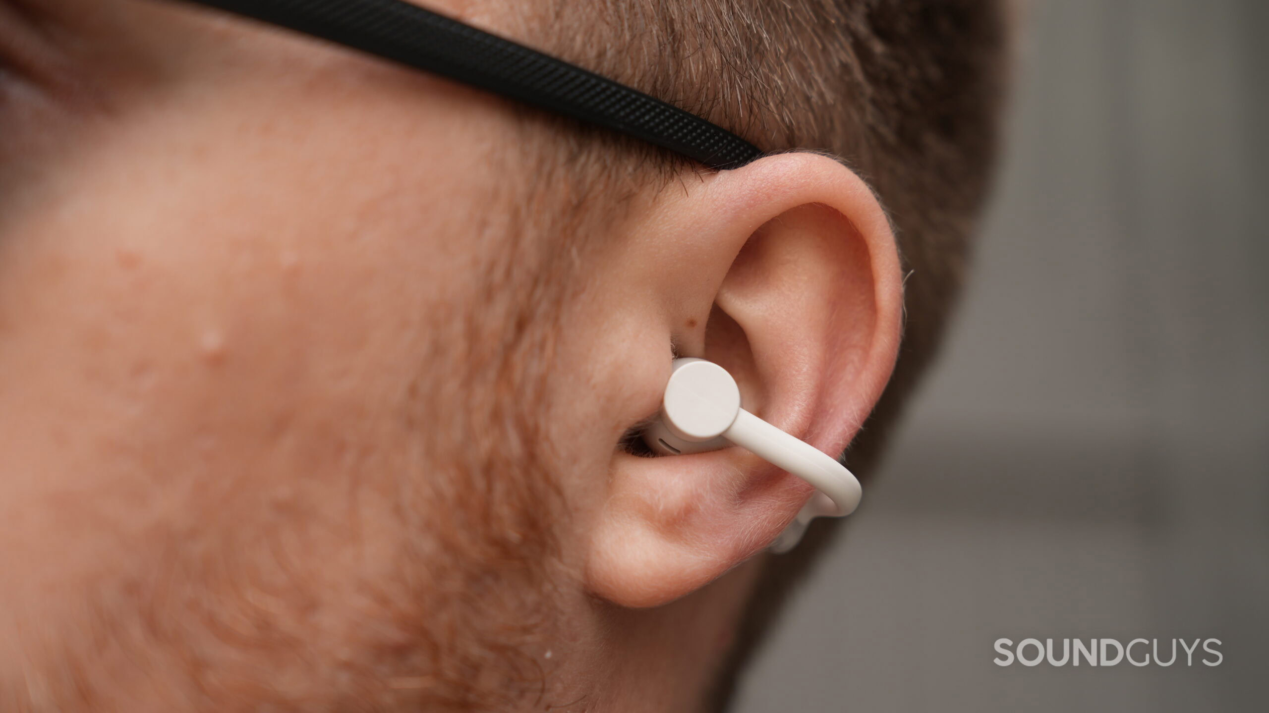 Close-up of a white CMF Clip Pro earbud clipped around a man’s ear.