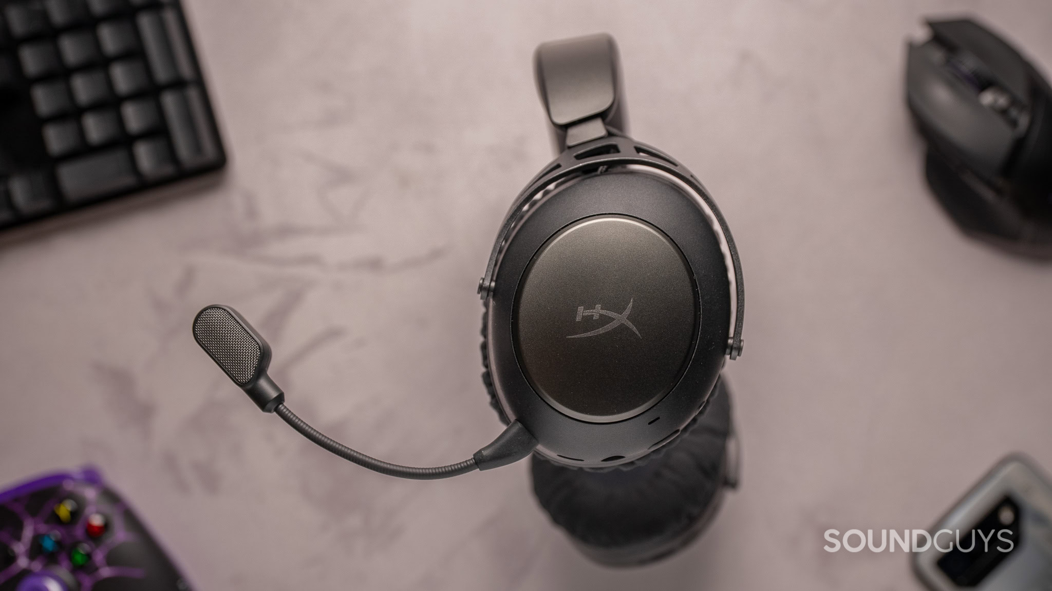 Top down view of the HyperX Cloud Alpha 2 headphones with peripherals in the background.